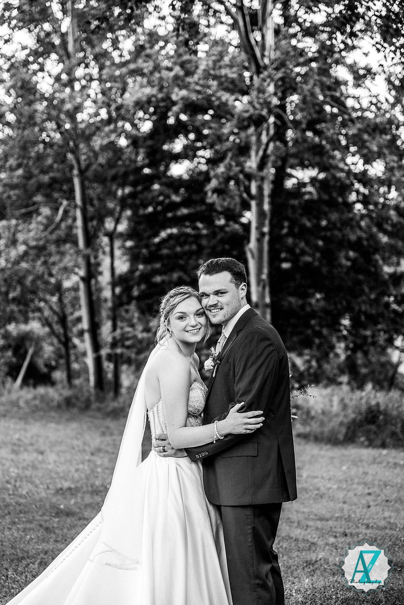 A romantic outdoor wedding photo series showing a couple in formal attire embracing on grassy grounds with trees.