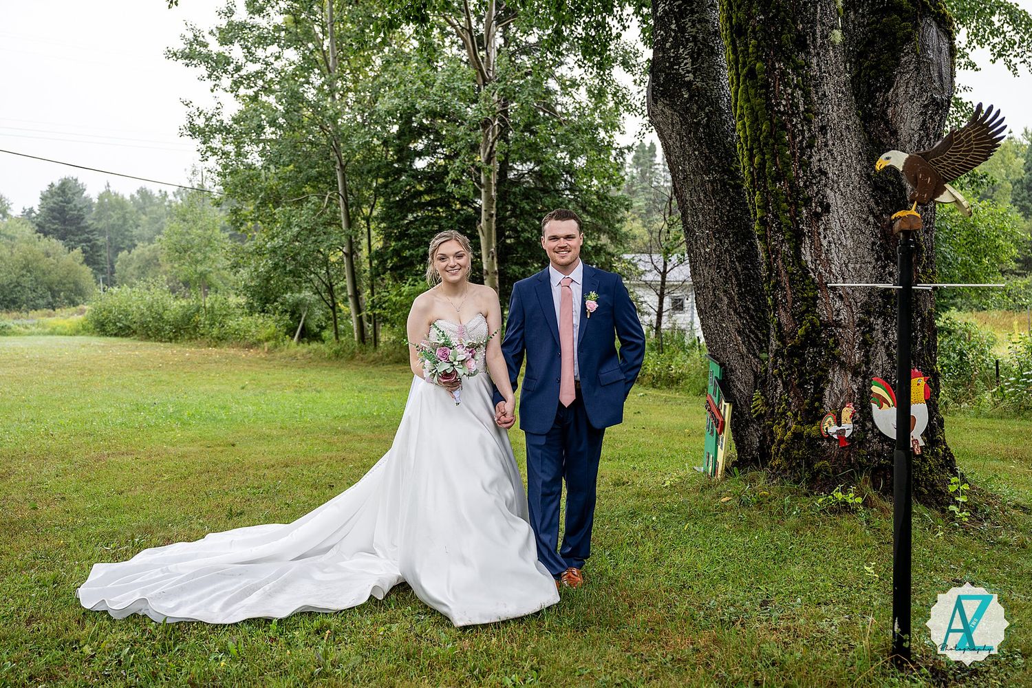 Wedding couple poses in lush green settings showing the elegant train of a white wedding dress trailing on grass.