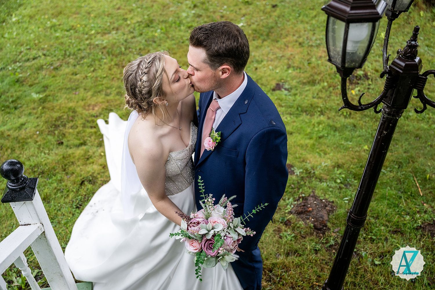 Newlywed couple share romantic kisses in a lush garden setting with black lantern posts in the background.