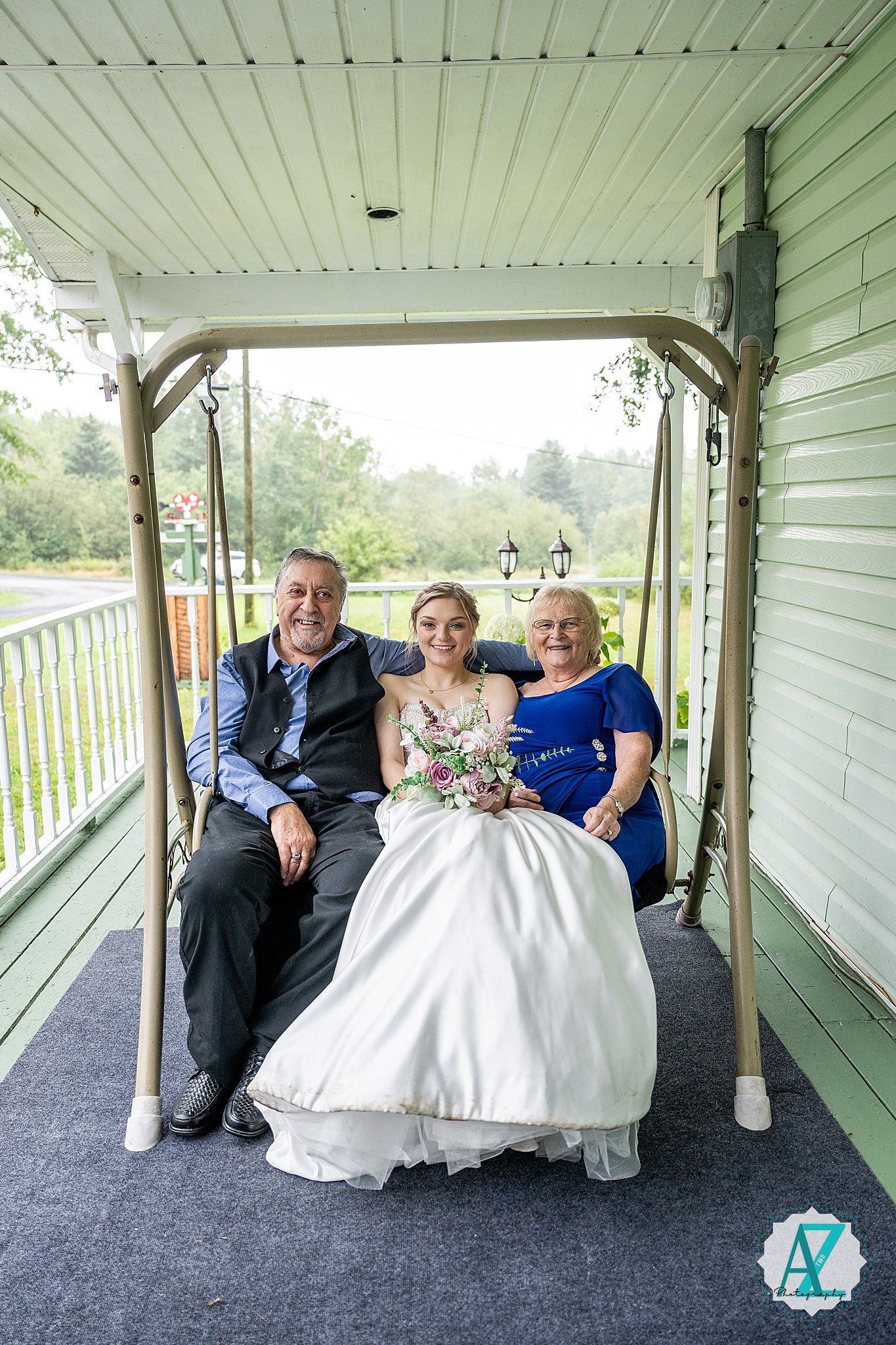Wedding party members seated on a covered porch with blue carpet and white railings.