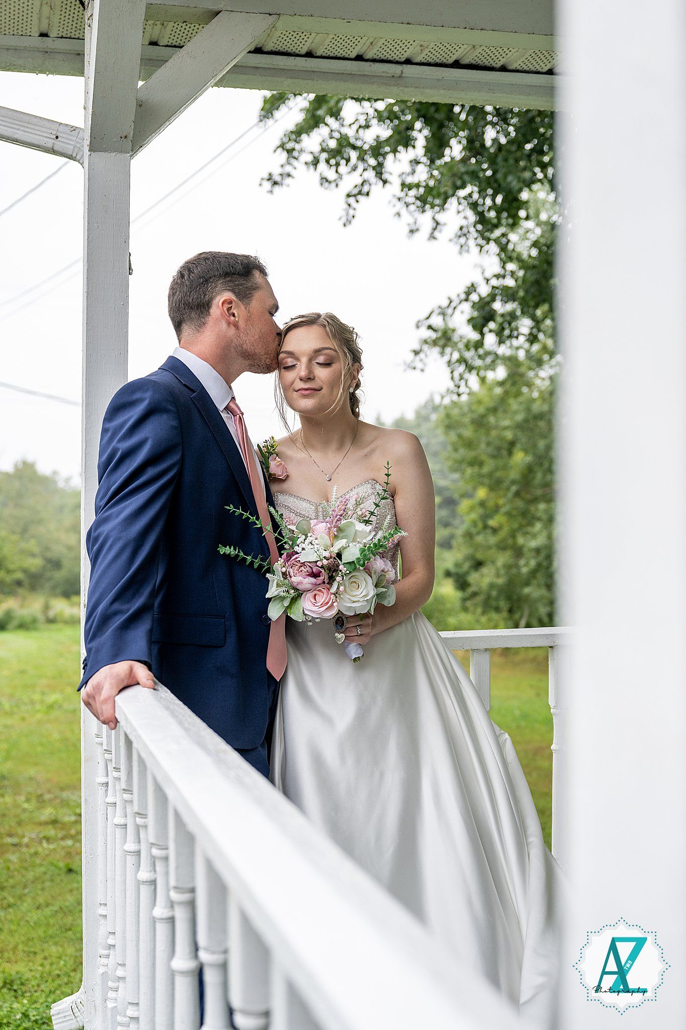 A romantic moment between newlyweds under a white gazebo surrounded by lush greenery.