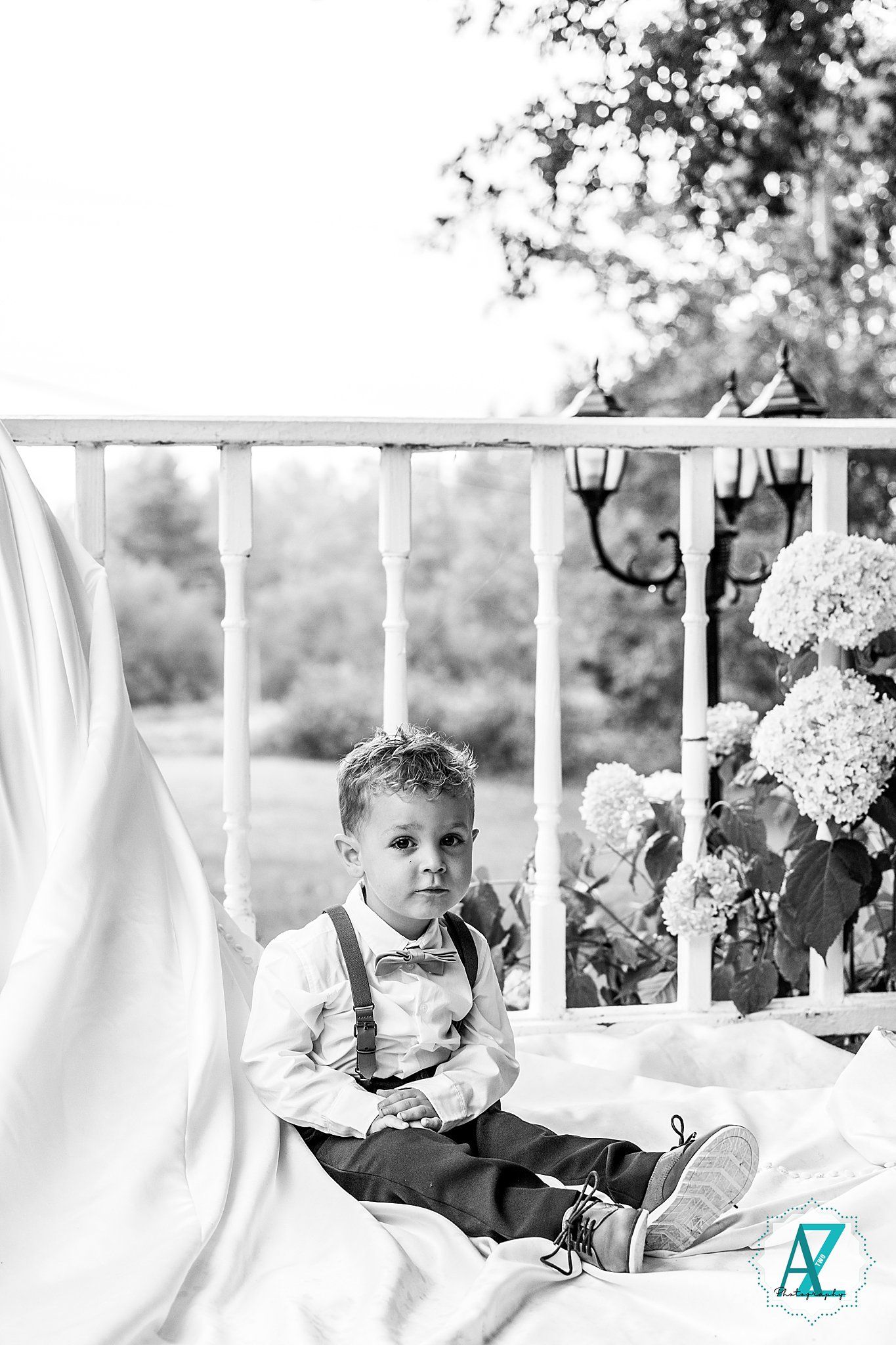 Black and white photo of wedding details with white linens and floral arrangements outdoors.