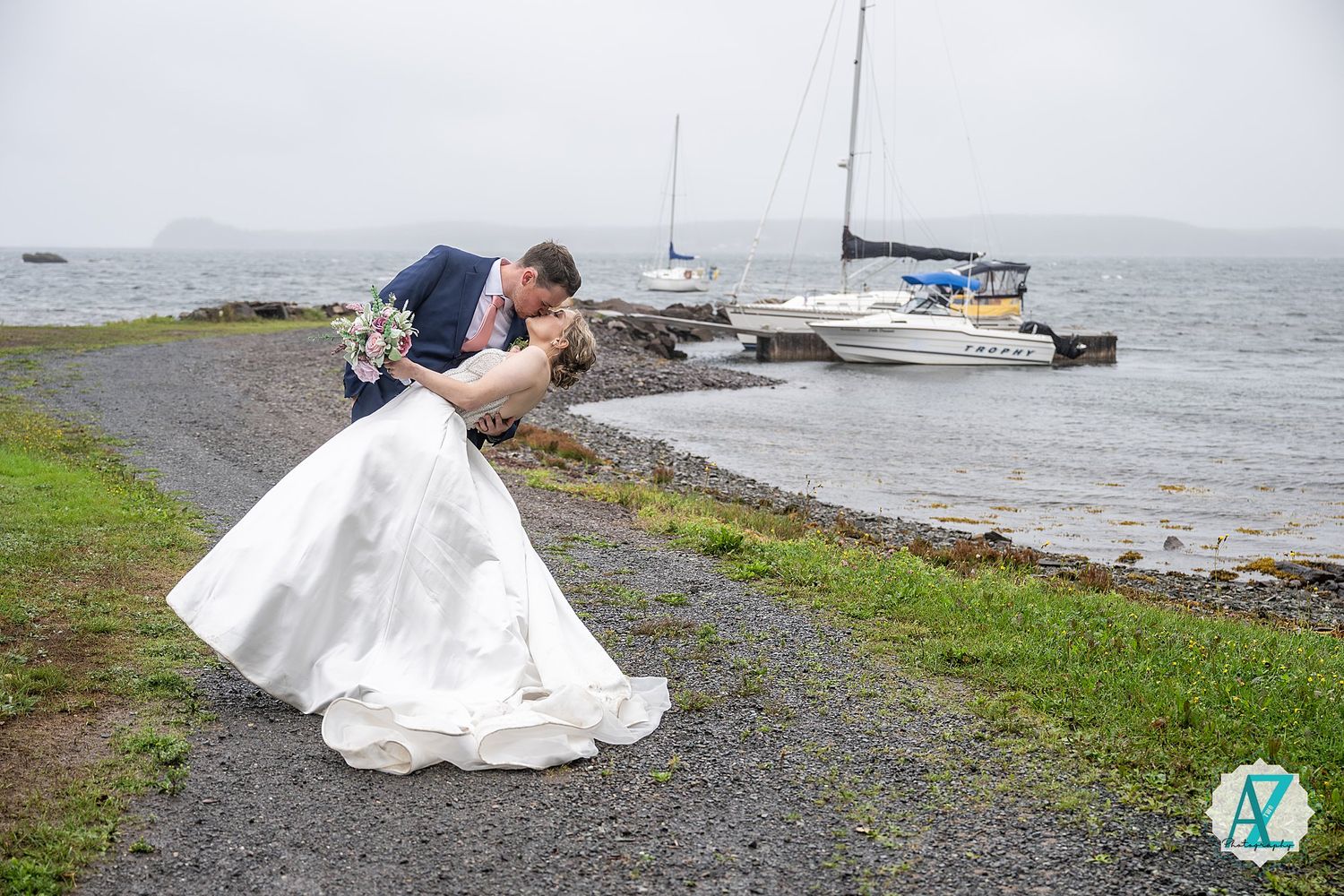 A scenic oceanside photo shoot featuring white formal attire against a dramatic coastal backdrop with overcast skies.