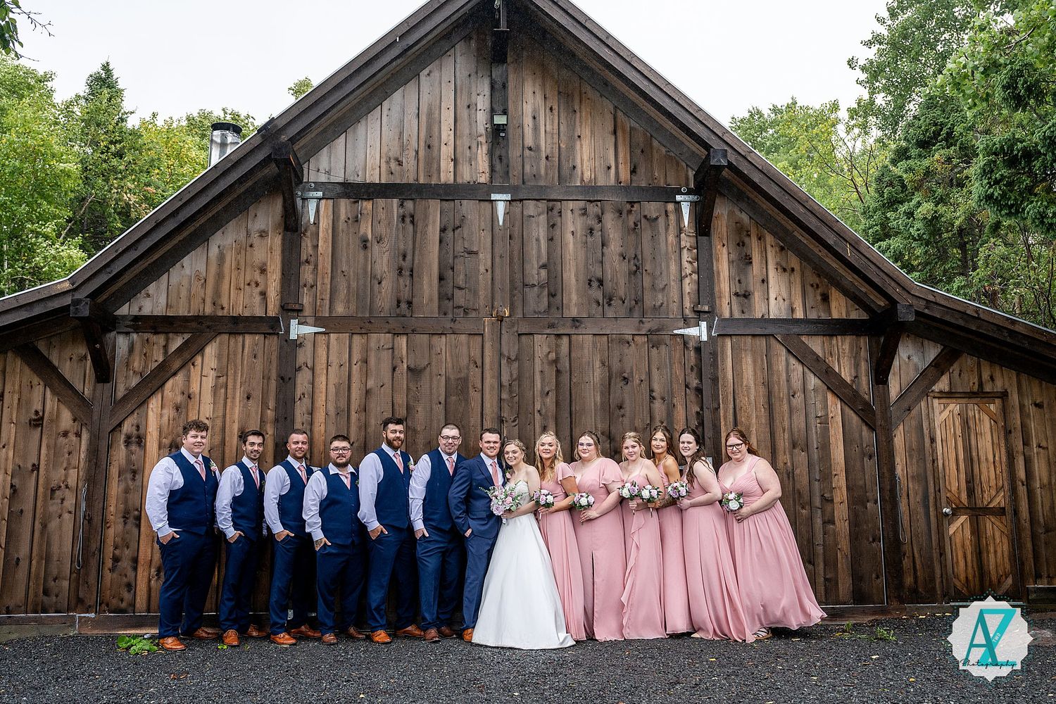 Wedding party lineup in front of rustic wooden barn with navy blue and pink color scheme.