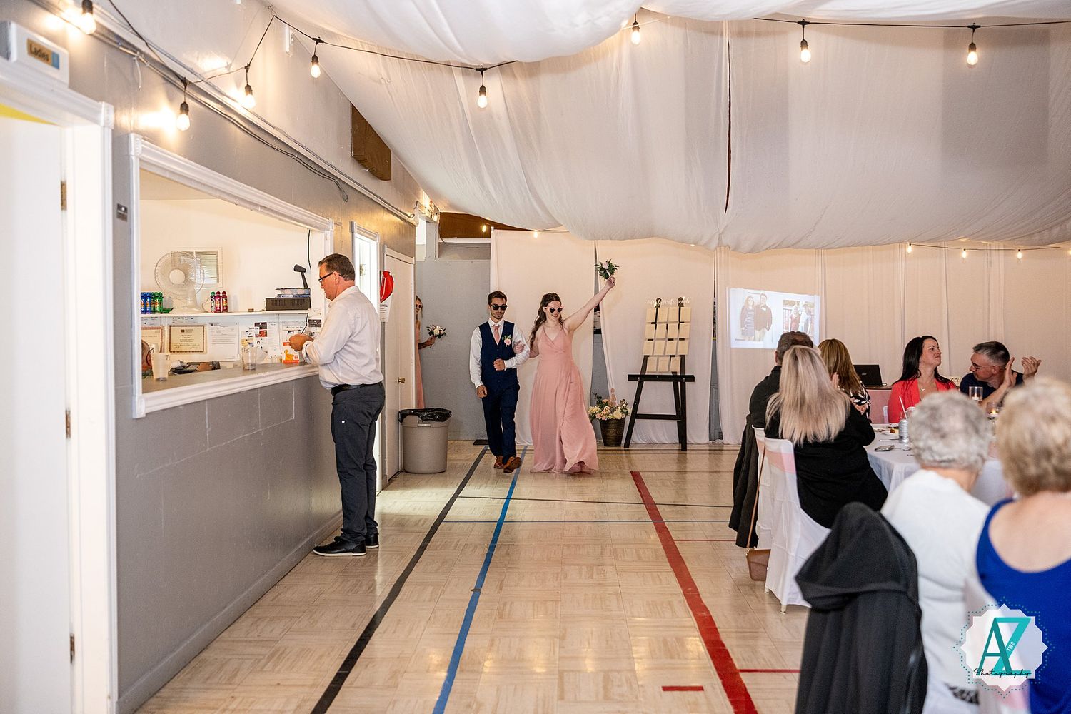 Indoor venue decorated with string lights and white fabric draping for an elegant event setup.