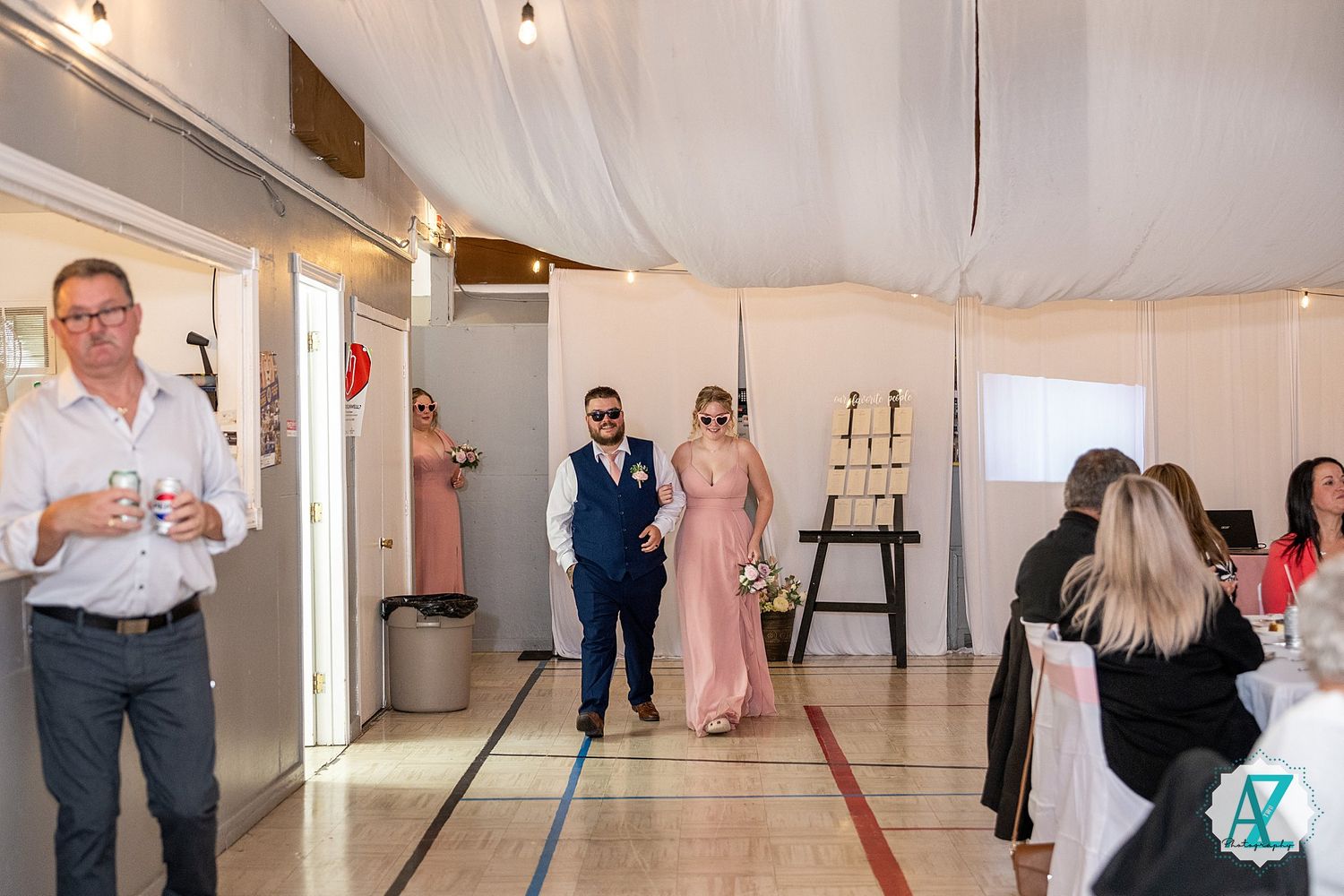 Guests gather in an elegant reception venue with white drapes and candlestick holders during a special celebration.