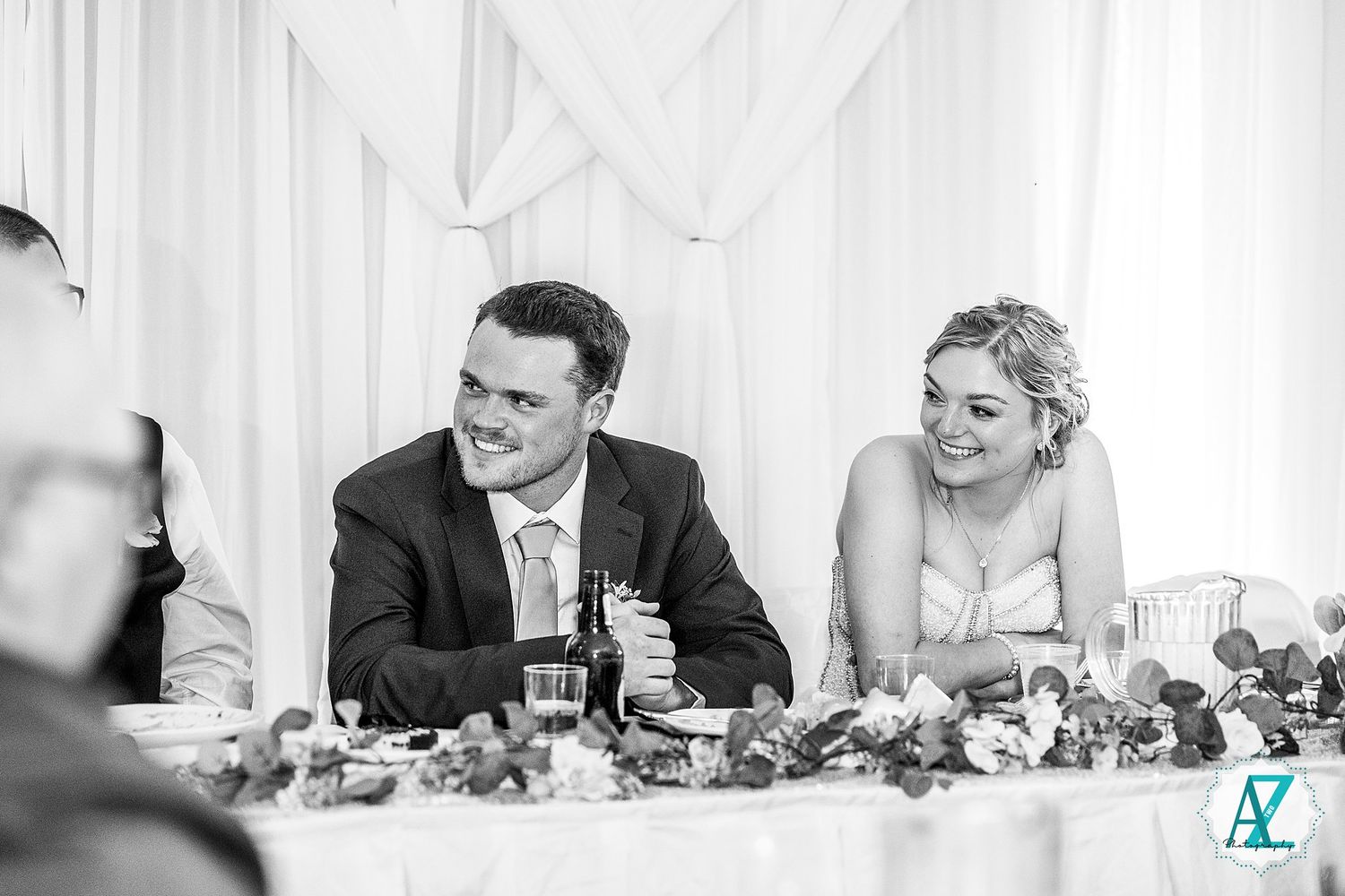 Wedding guests laughing and enjoying themselves at a reception table covered in white linens and decor.