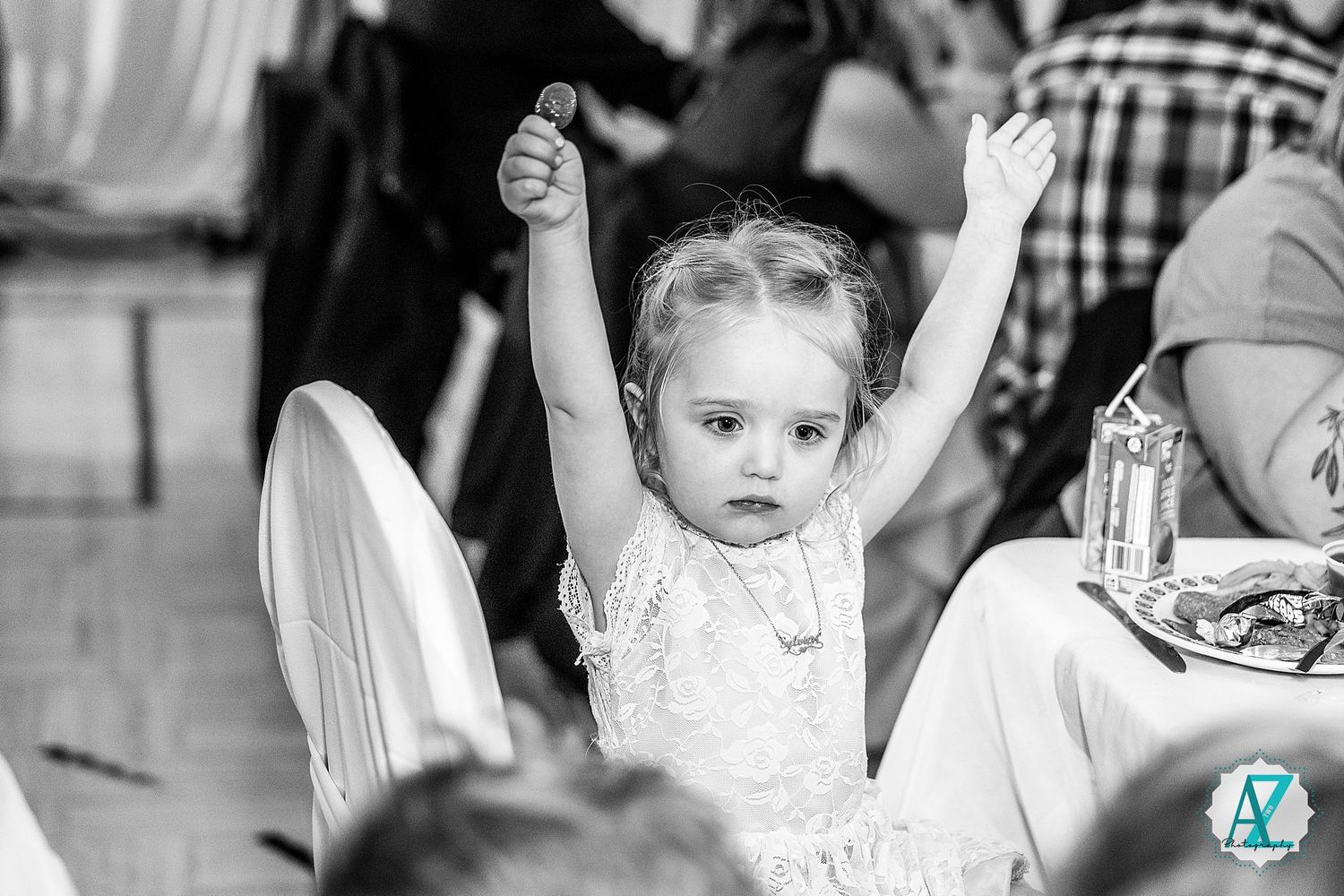 Group of children raising their hands and participating enthusiastically during an indoor activity or event.