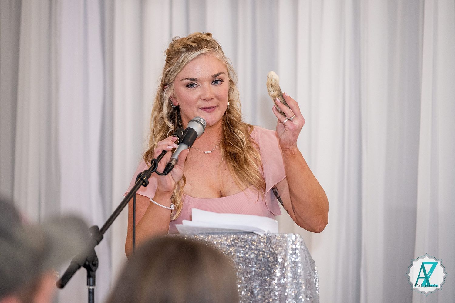 Reception guests raising glasses in celebration during wedding toasts with white curtain backdrop.