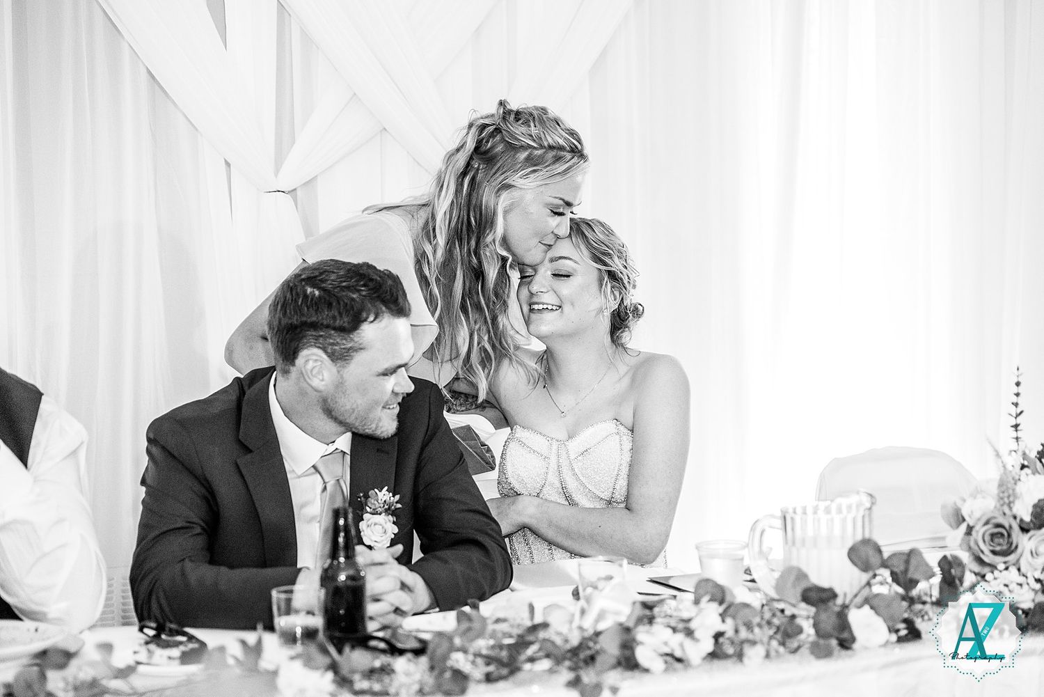 Black and white candid shot of wedding party enjoying emotional moments during reception.