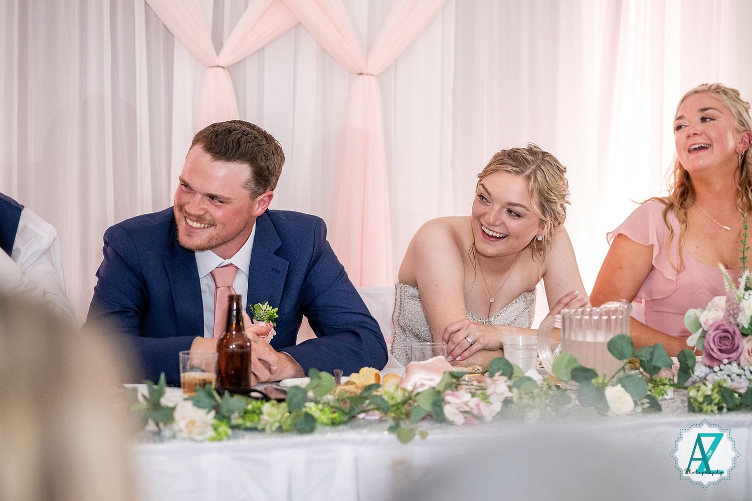 Happy guests enjoying conversations and laughter at a wedding reception with soft pink lighting.
