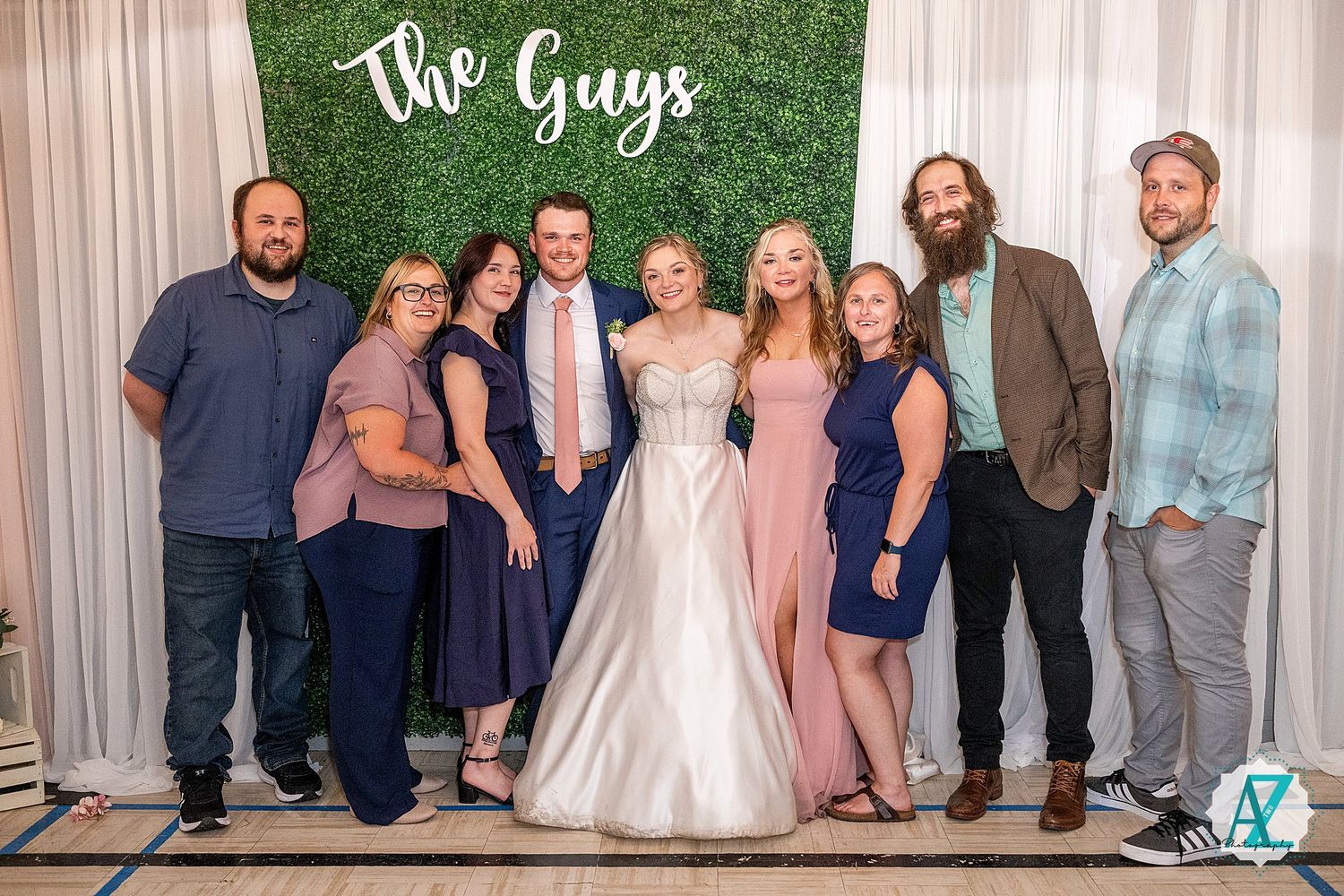 Wedding photo backdrop featuring green wall with white curtains and elegant text signage.