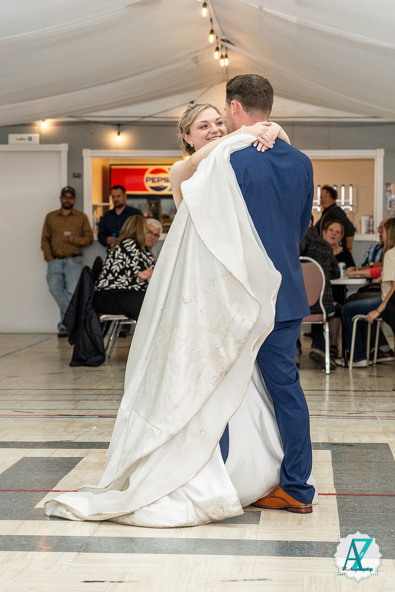 Wedding couple performs romantic dip dance move on spacious white dance floor during reception.