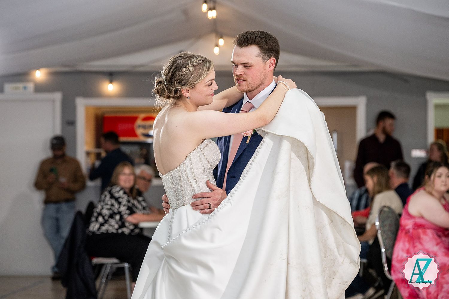 A couple shares a romantic first dance at their wedding reception while guests look on at their celebration.