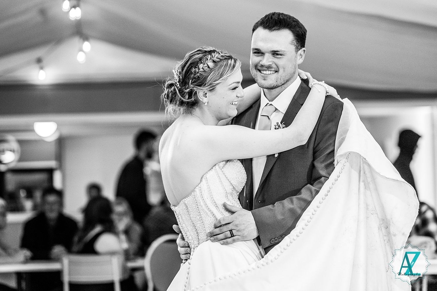 A couple shares a romantic dance at their wedding reception while guests look on.