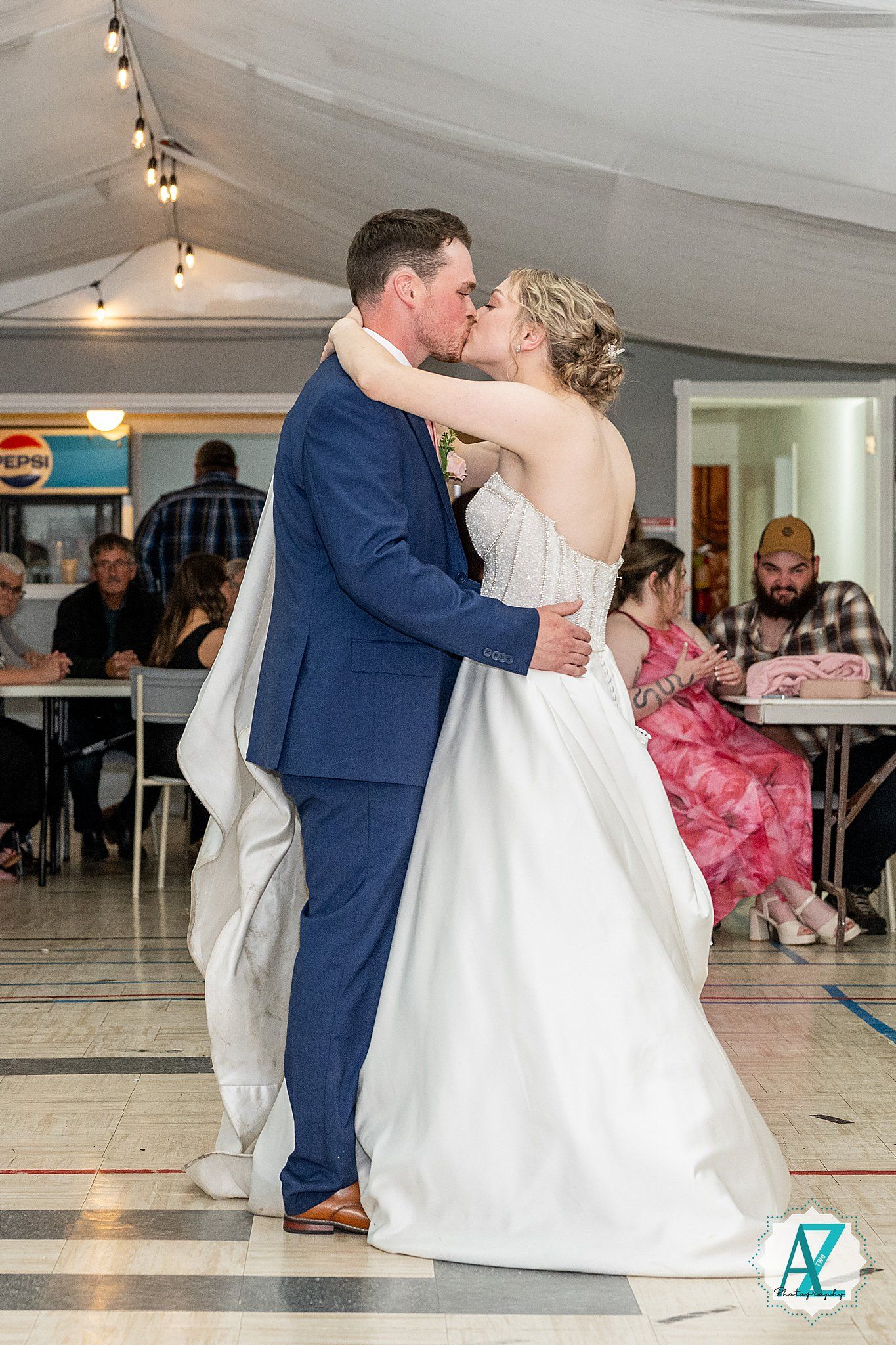 A romantic first dance between newlyweds with the bride in white and groom in blue during their wedding reception.