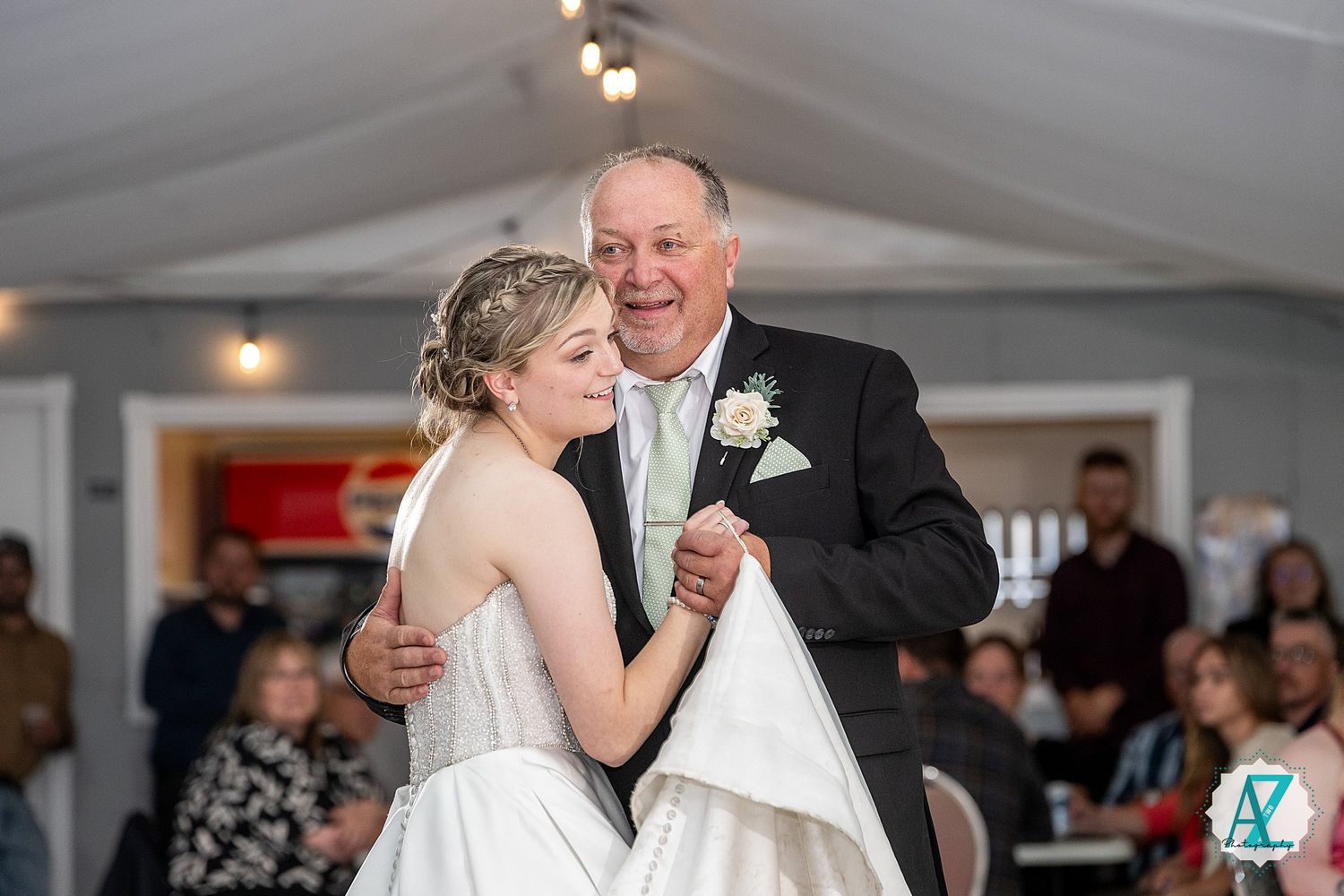 A wedding couple shares a dance on the ballroom floor surrounded by guests during a joyful reception celebration.