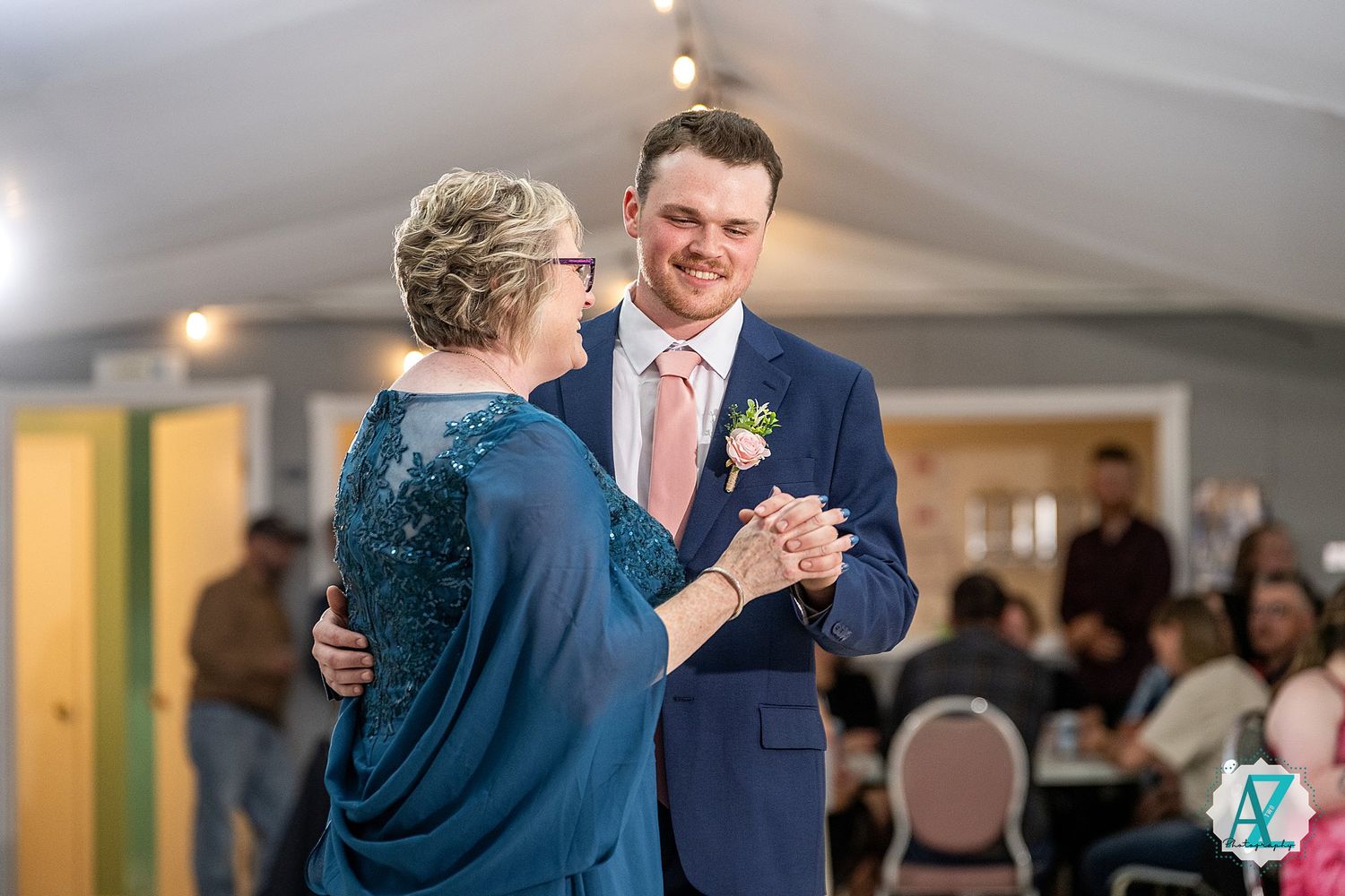 A couple shares a tender dance moment in formal attire on their wedding day in an indoor venue.