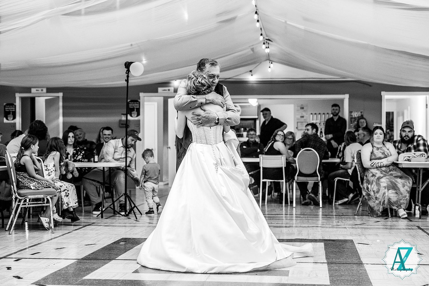 Black and white panoramic view of a wedding reception venue showing a dance floor and seated guests.
