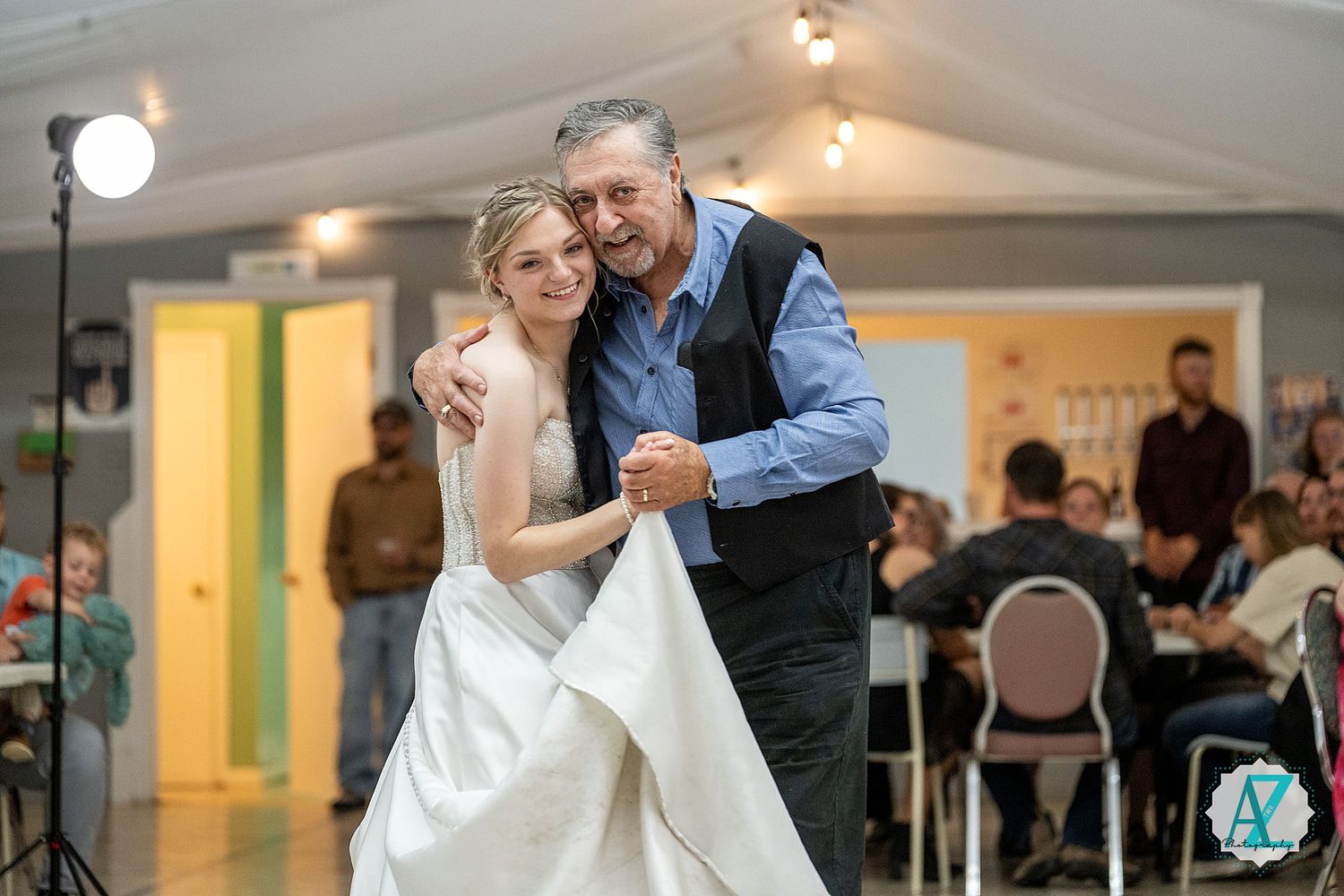 A tender moment during a wedding dance on a polished indoor ballroom floor with soft lighting overhead.