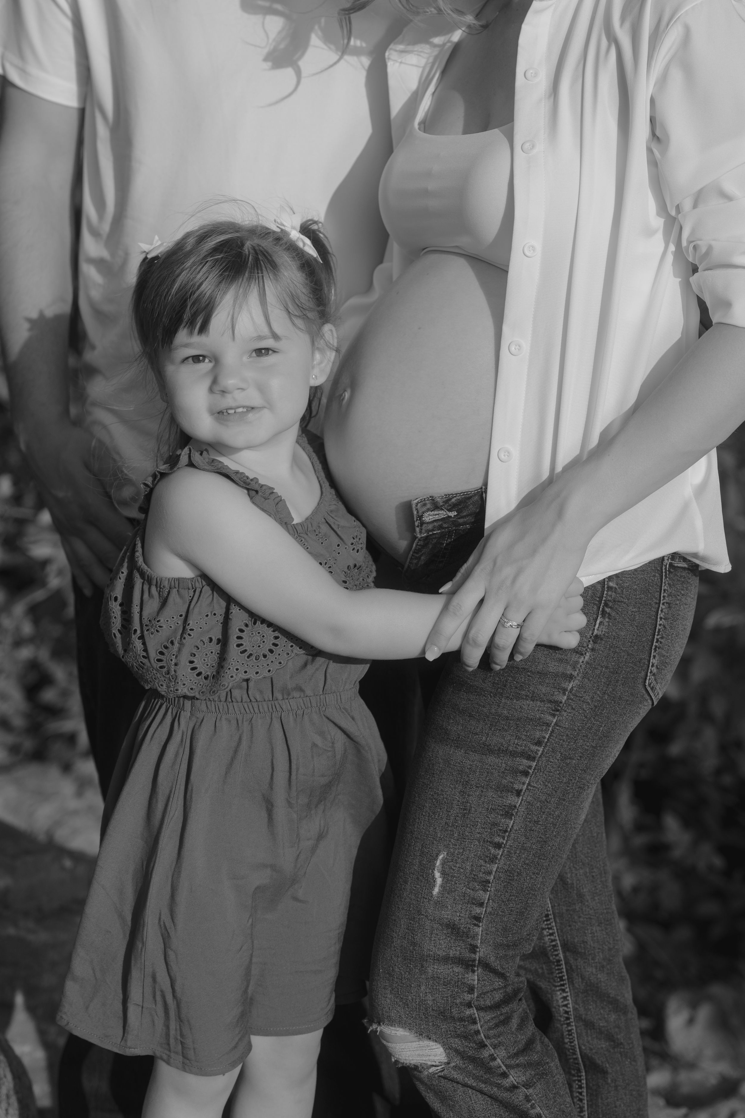 Black and white photo series showing a young child in a dress standing next to someone in jeans, captured from different angles.
