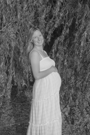A series of black and white outdoor portraits showing someone in a flowing white sundress posing against willow trees.