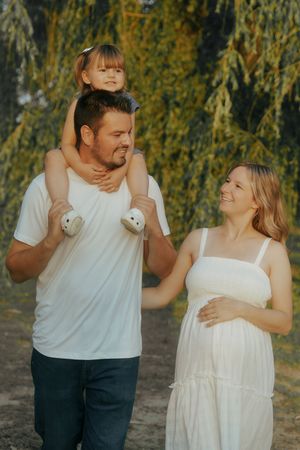 A couple in white and casual attire shares romantic moments together in a natural outdoor setting with autumn foliage.