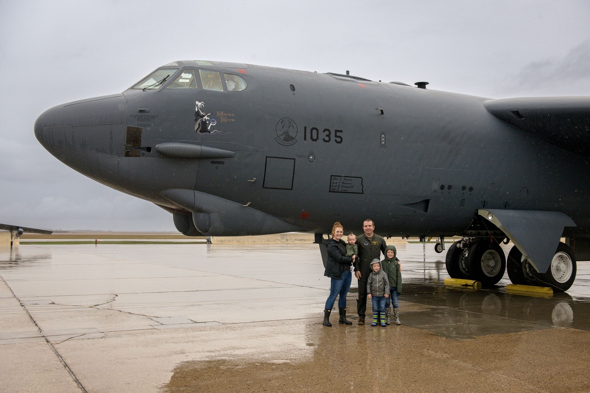 Military cargo aircraft lined up on an airfield under cloudy skies.