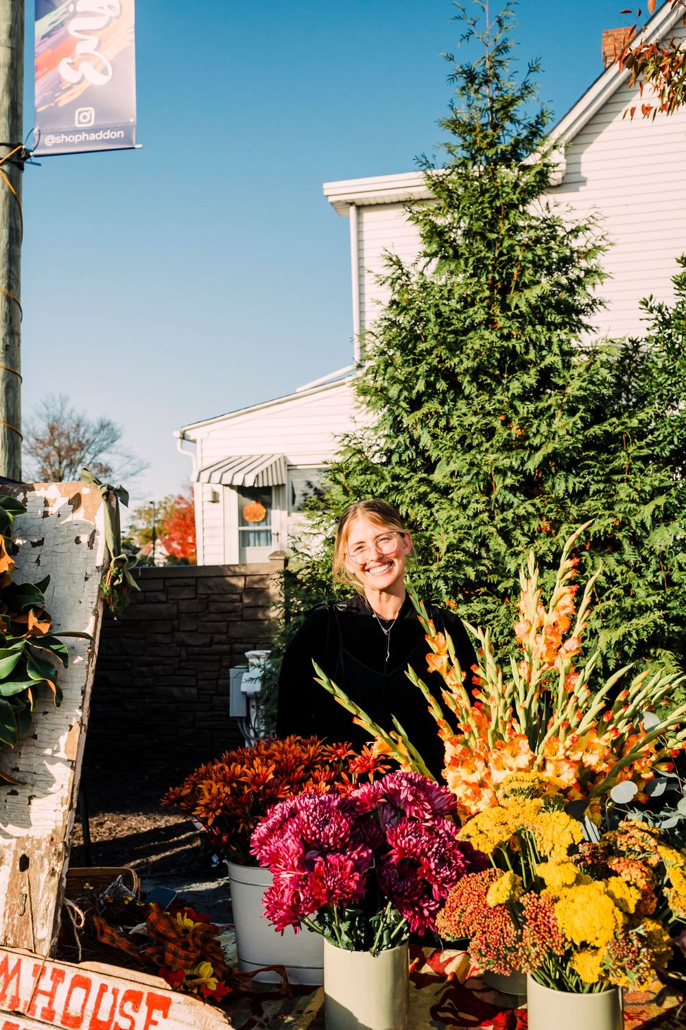 Colorful fall flower arrangements with pink, yellow and orange blooms decorate an outdoor market display.