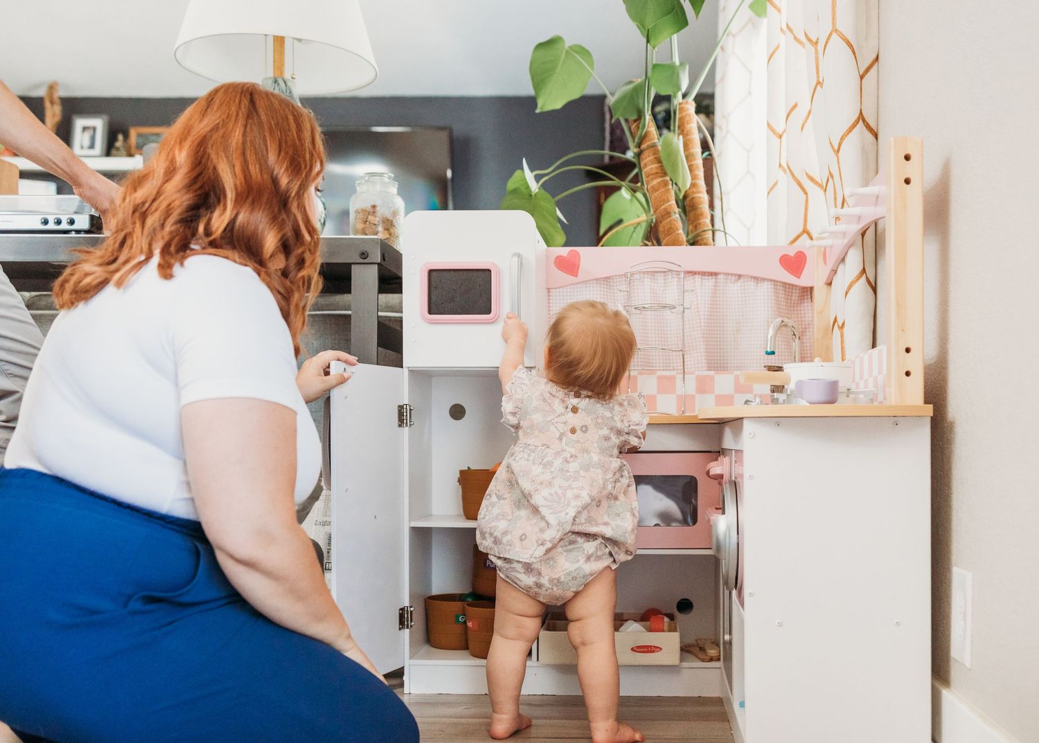 Parent and toddler organize kitchen cabinet together while childproofing home.