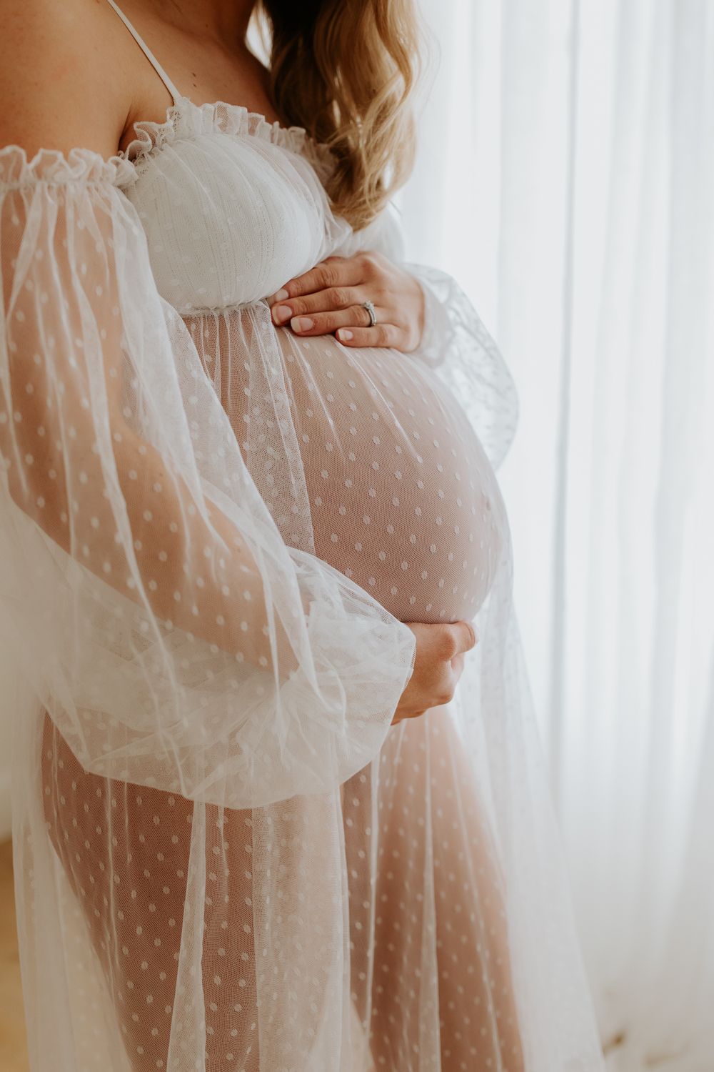 Pregnant woman modelling a flowing sheer gown that shows off her gorgeous bump in an Adelaide photography studio based in Tea Tree Gully.