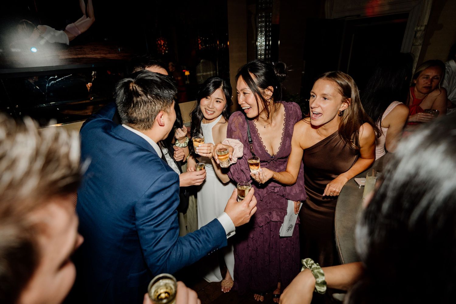 Reception guests dancing and celebrating on darkened dance floor.
