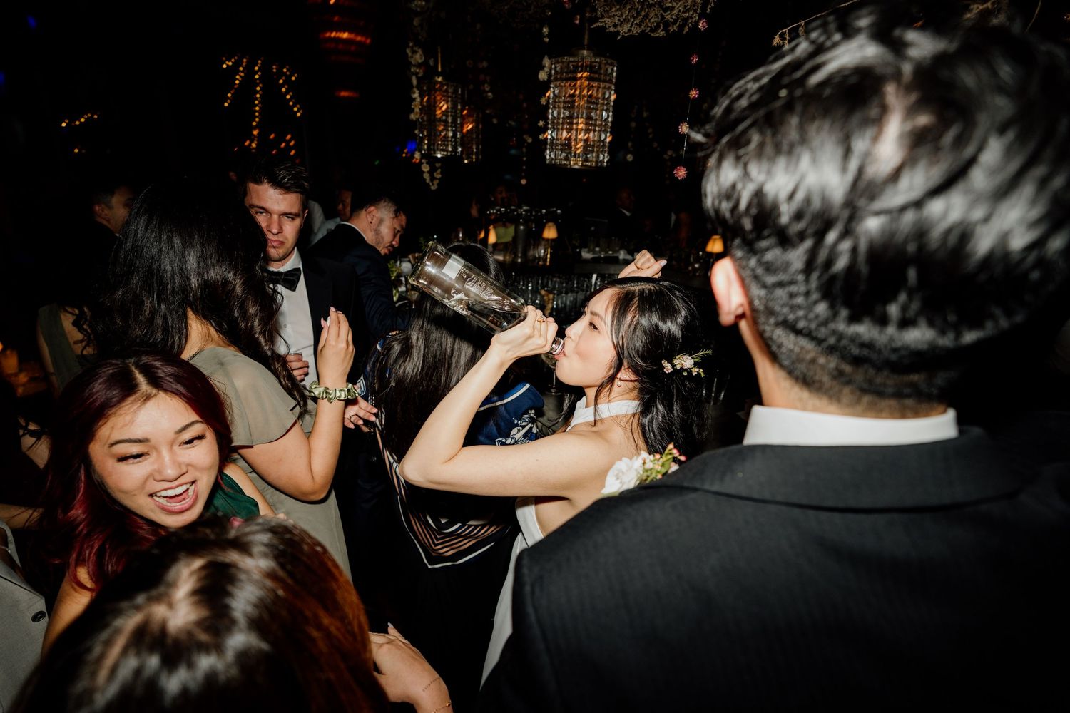 Wedding celebration captured in dark reception venue with dancing guests.