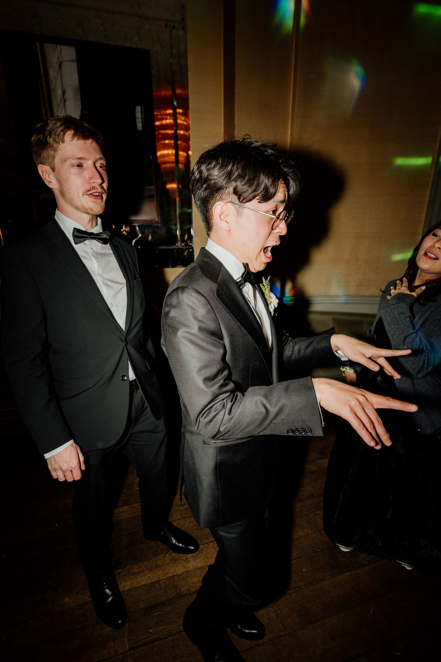 Guests dancing and having fun at a dimly lit wedding reception party.