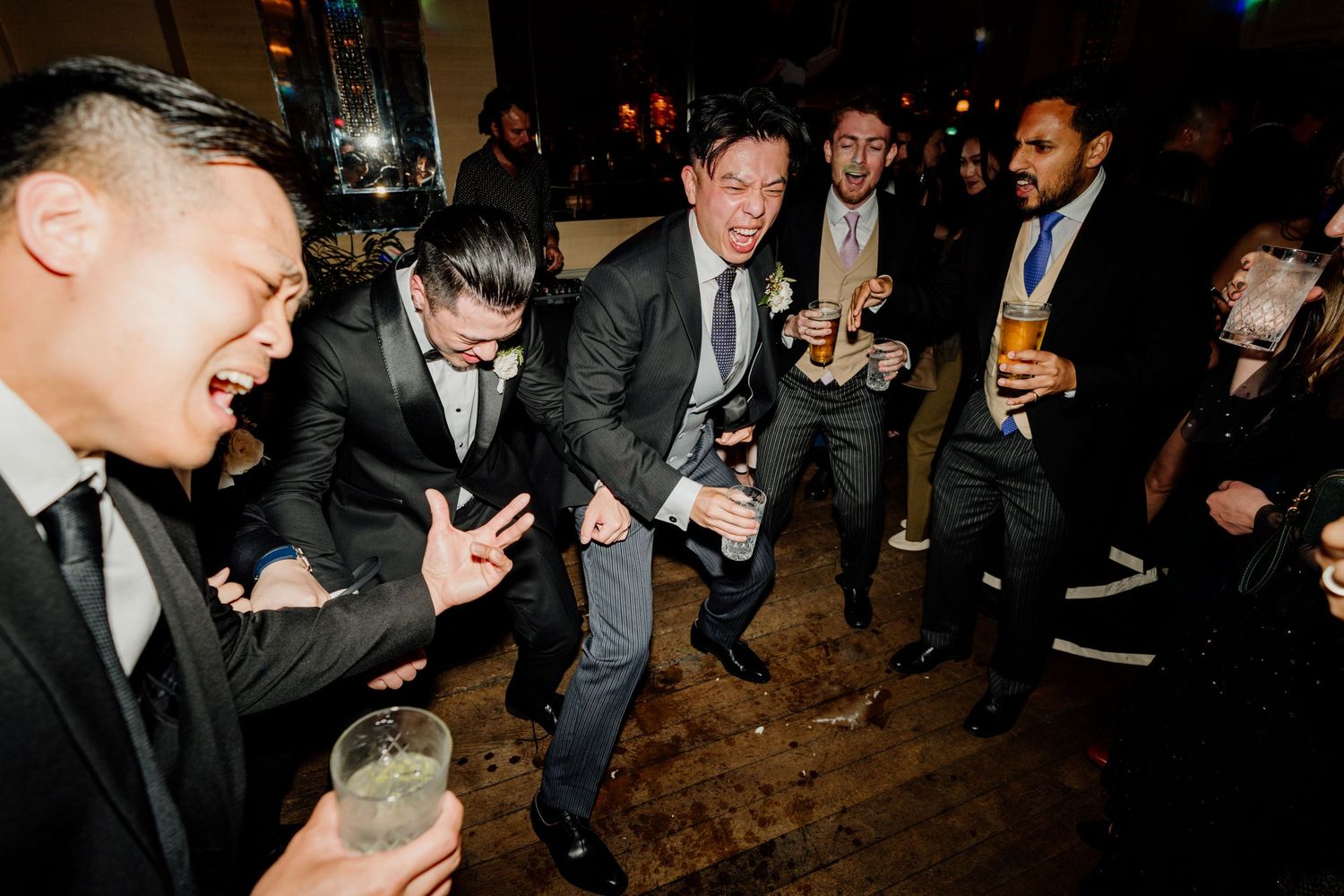 Wedding guests dancing and celebrating at nighttime reception party.