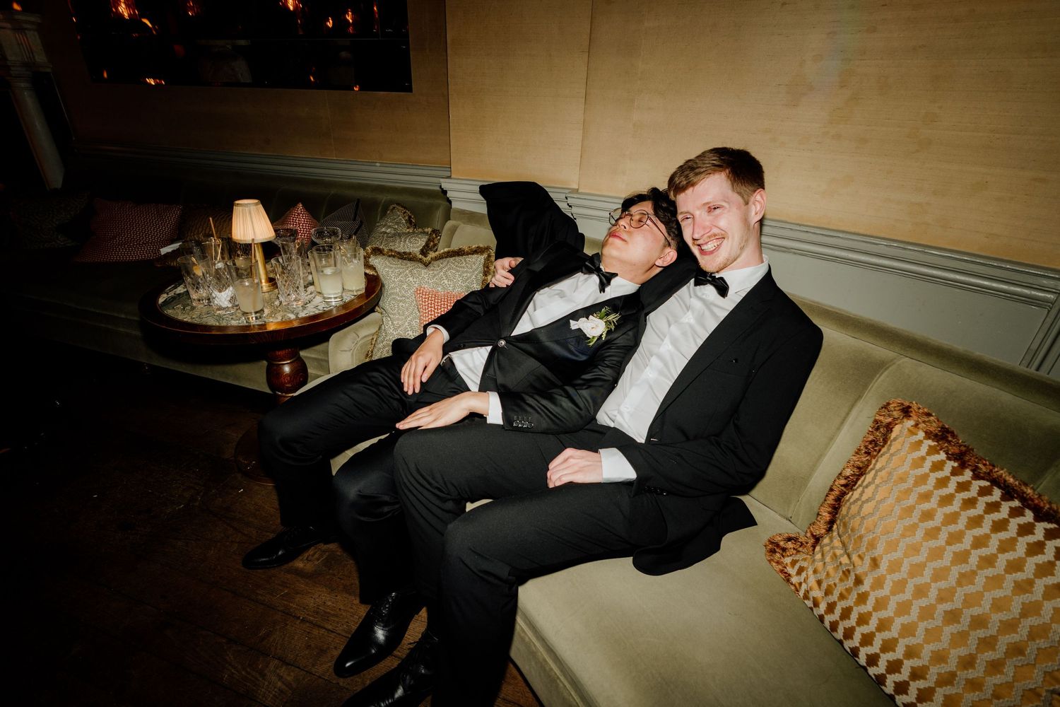 Candid moments of wedding couple lounging on a vintage couch in formal attire.
