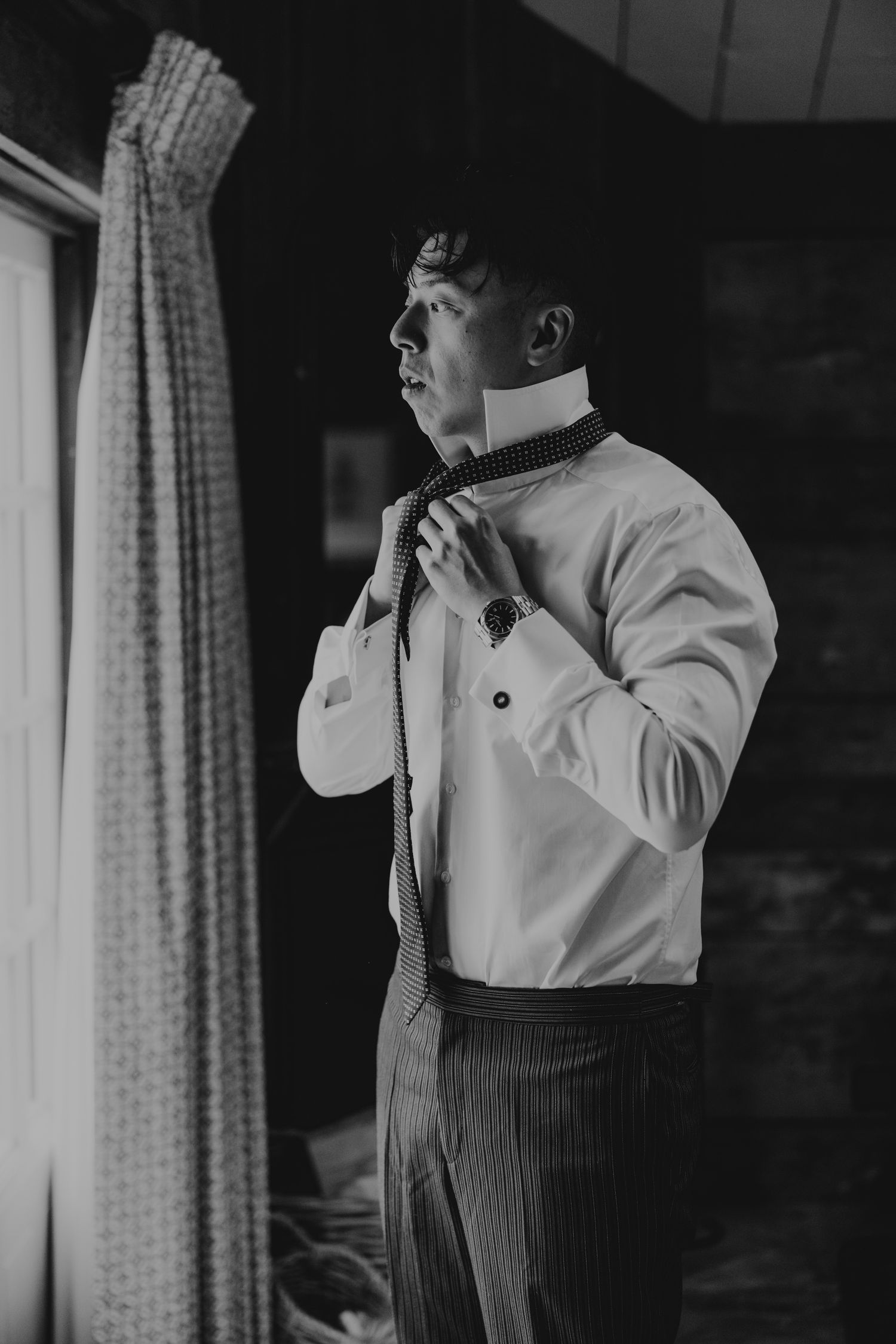 Artistic black and white portraits of someone adjusting a bowtie before the ceremony.