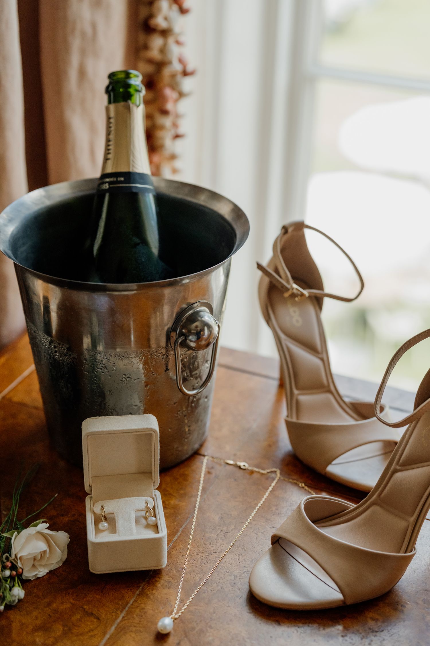 Wedding details including champagne in an ice bucket and elegant nude heels.
