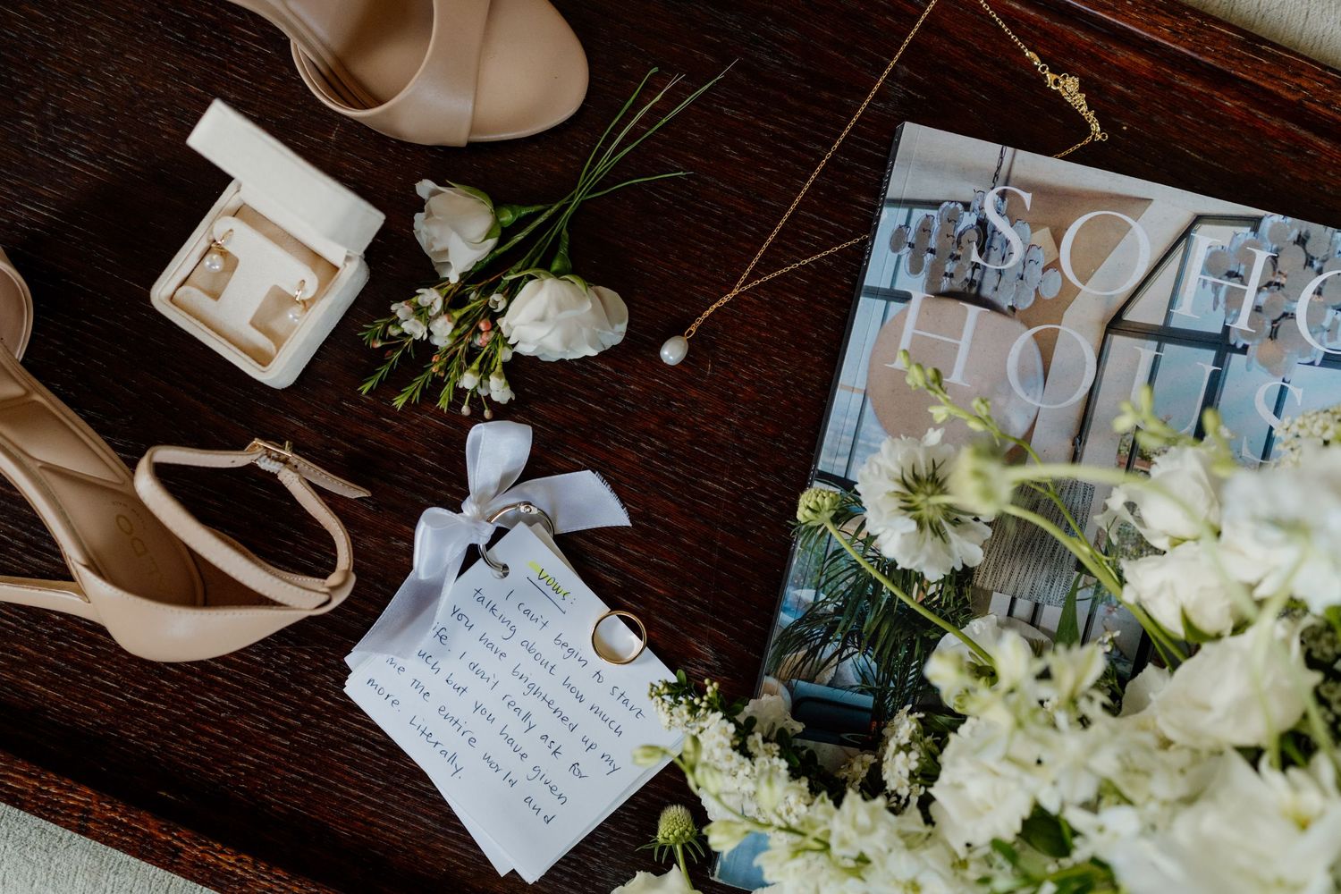Wedding details including handwritten notes and white floral arrangements on a dark wooden surface.