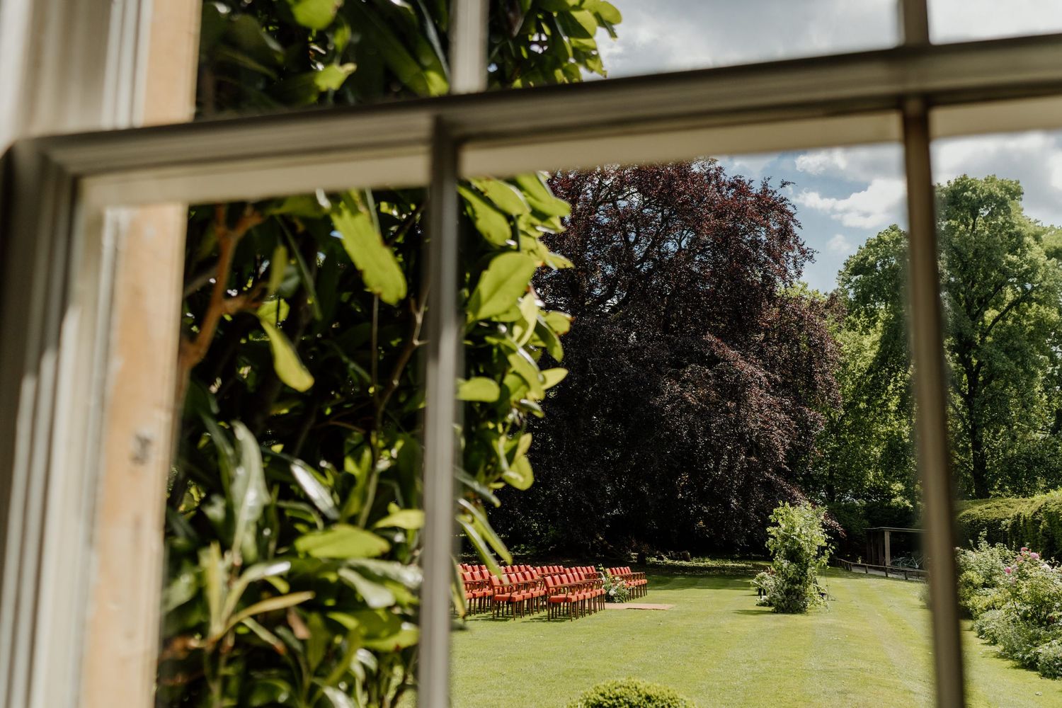 Sunlit windows with green plants and garden view at wedding venue.
