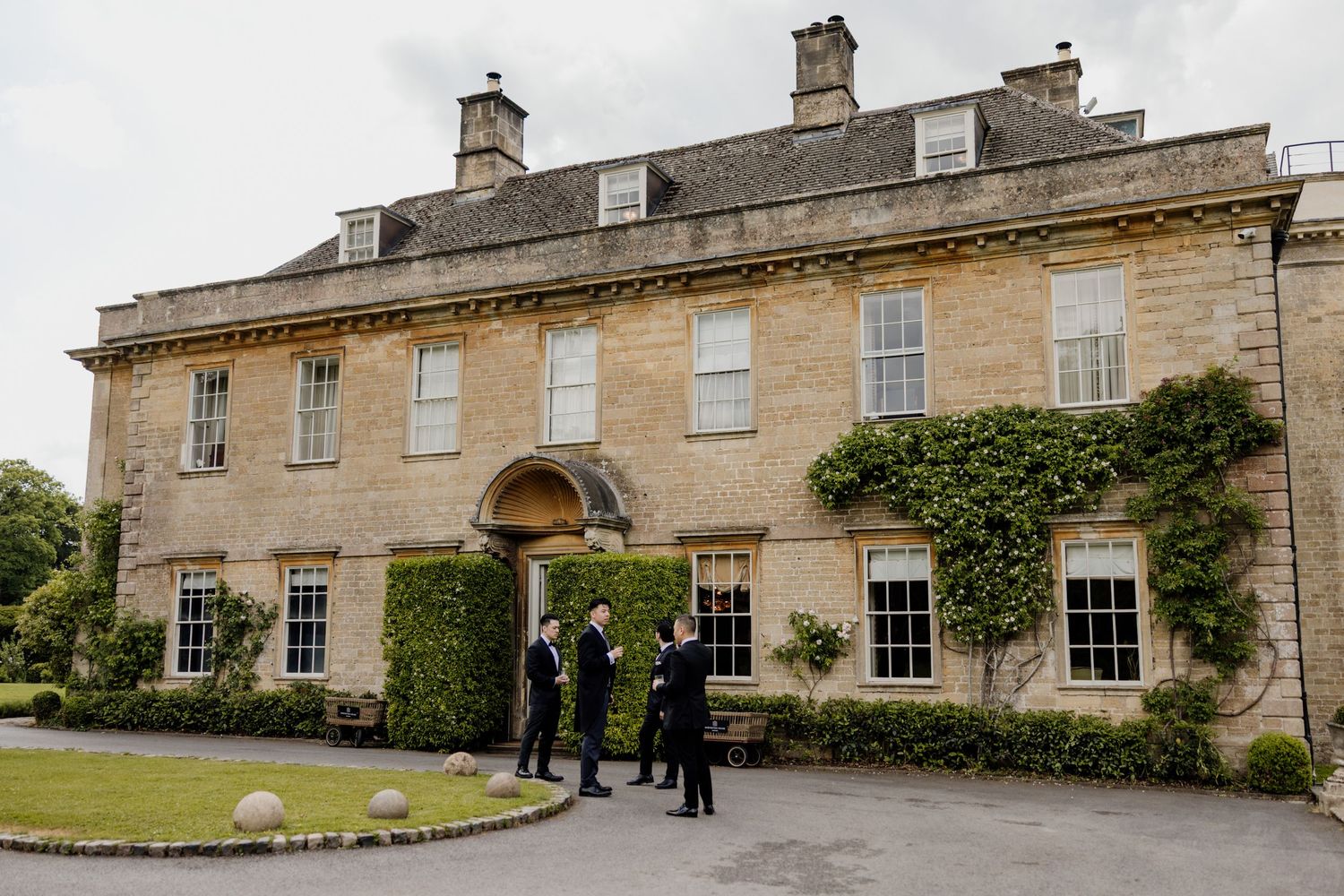 Panoramic view of an elegant stone manor house with manicured grounds.