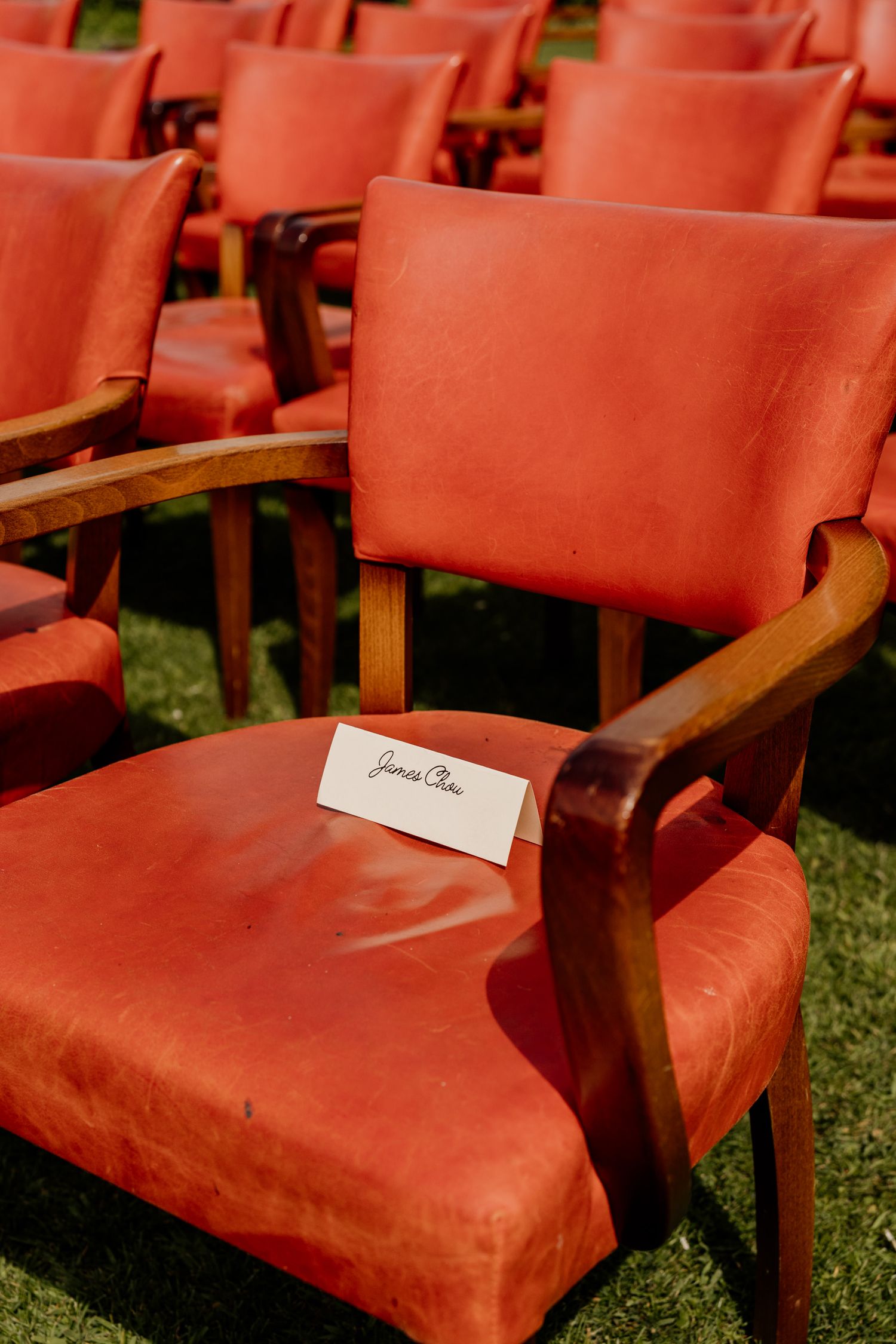 Red velvet chairs set up with name cards for wedding ceremony.