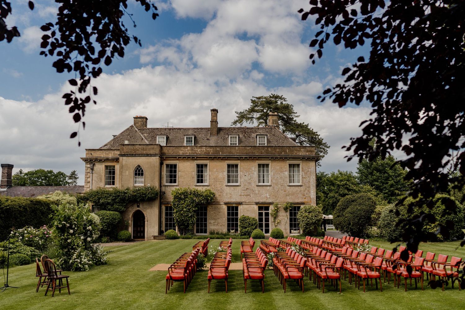 Panoramic view of an elegant country estate with outdoor seating arrangements under a bright blue sky.