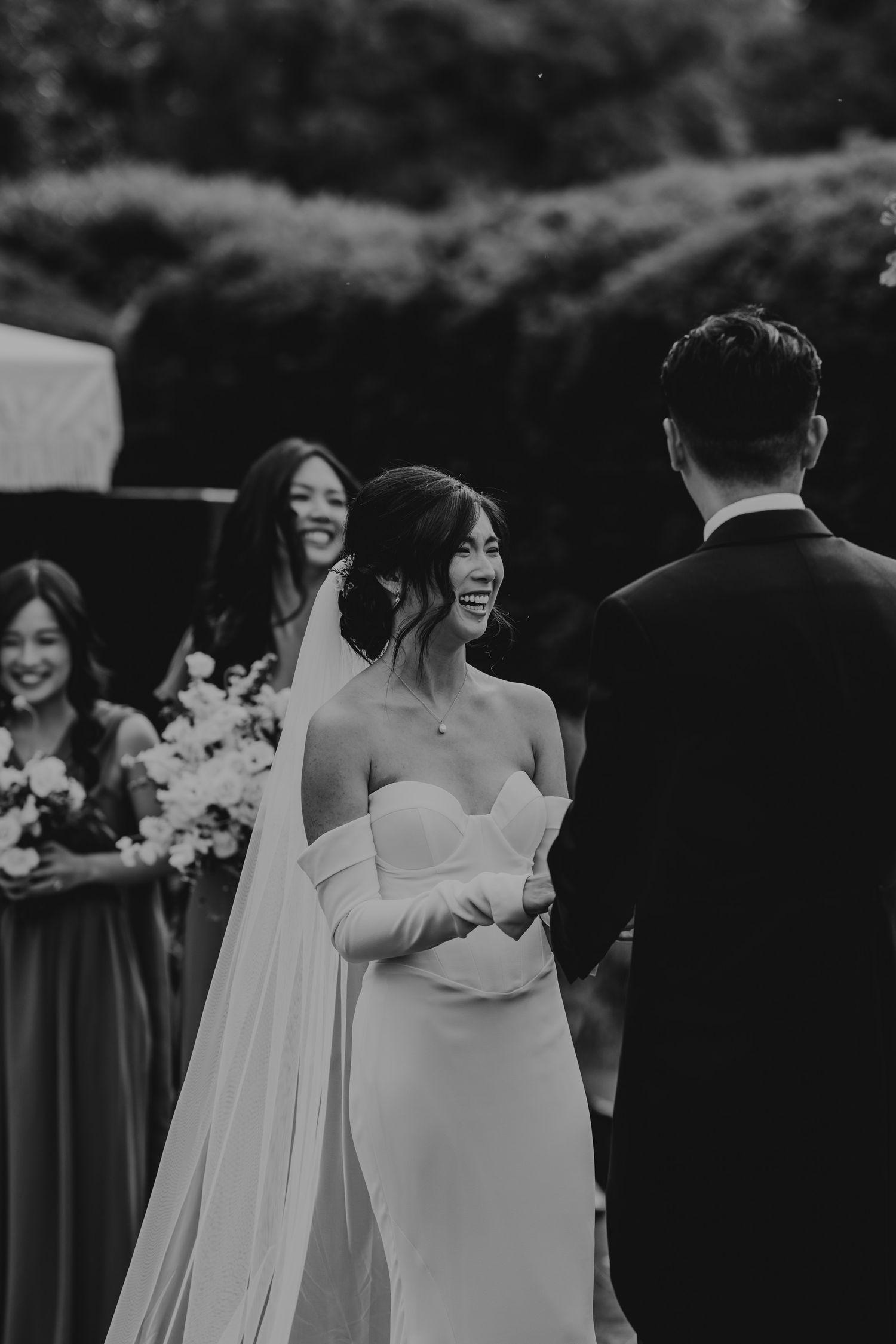 Black and white photo of wedding guests watching an emotional outdoor ceremony.