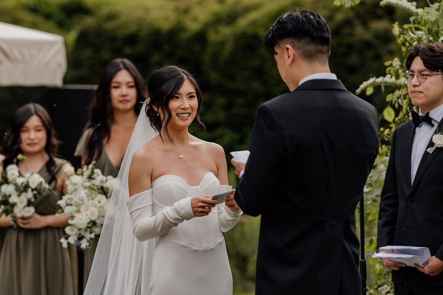 Outdoor wedding ceremony with guests watching beneath blue skies at an elegant estate.