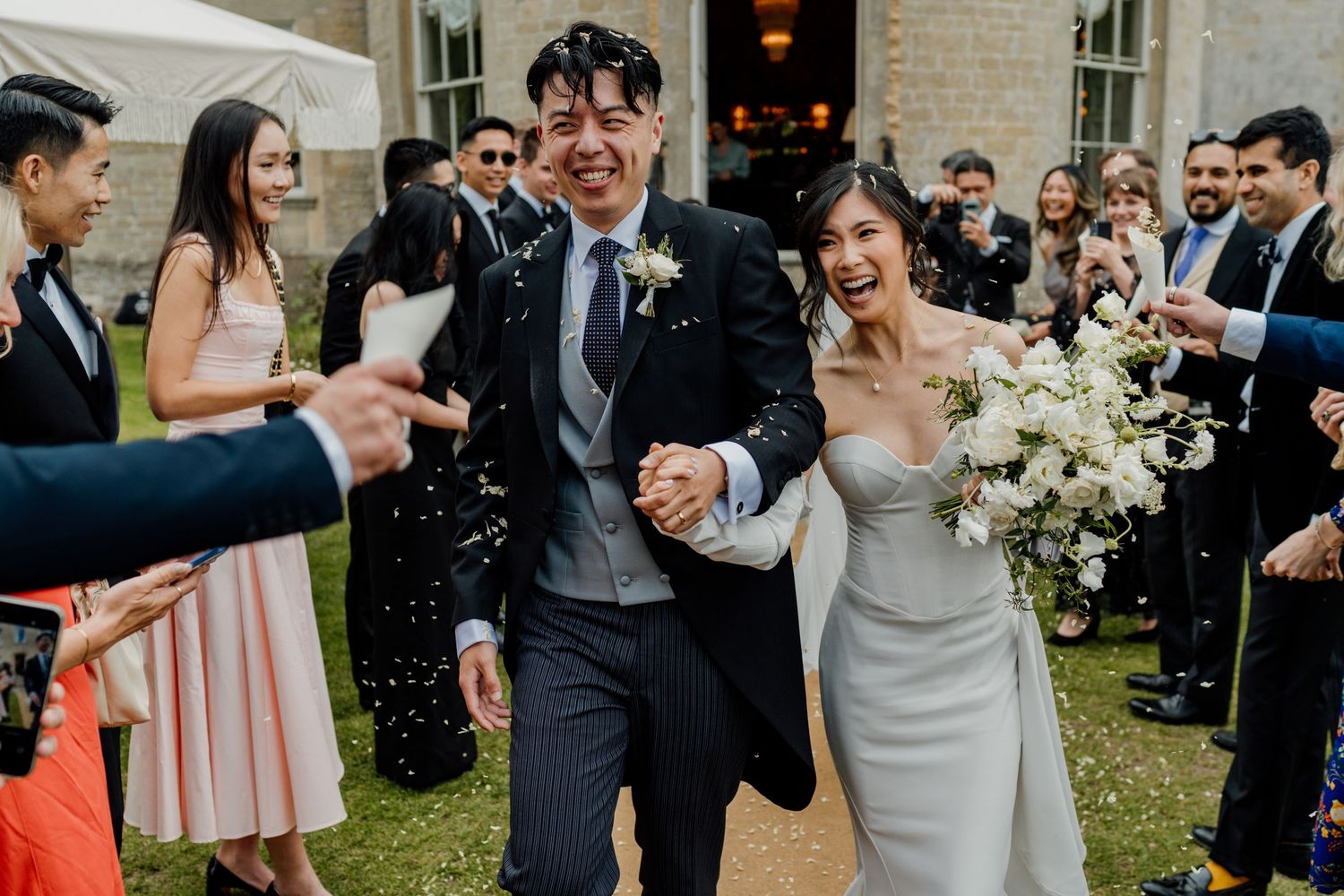 Joyful wedding celebration with confetti being thrown outside a historic brick building.