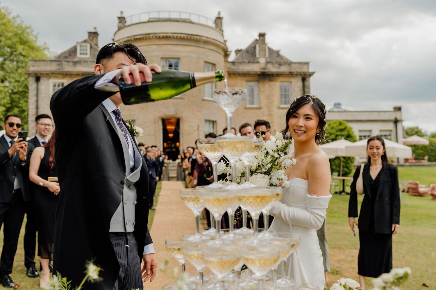 Wedding guests gather in a garden setting for outdoor celebration photos at an elegant estate venue.