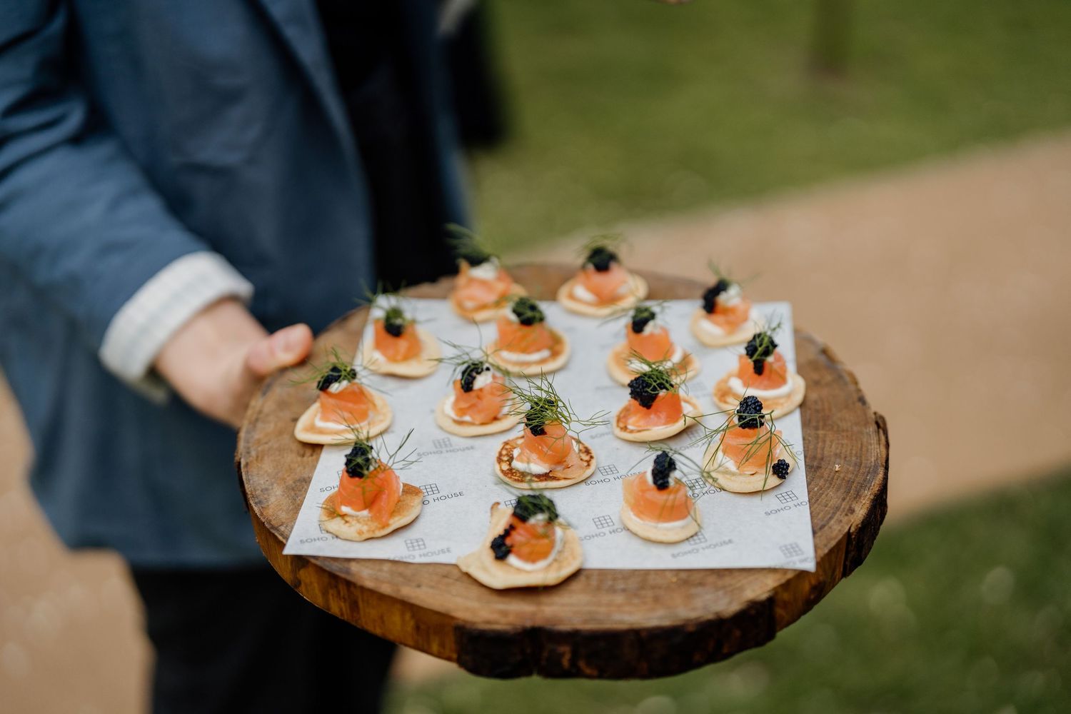 Appetizer plates being served at an outdoor catering event featuring smoked salmon bites on white platters.