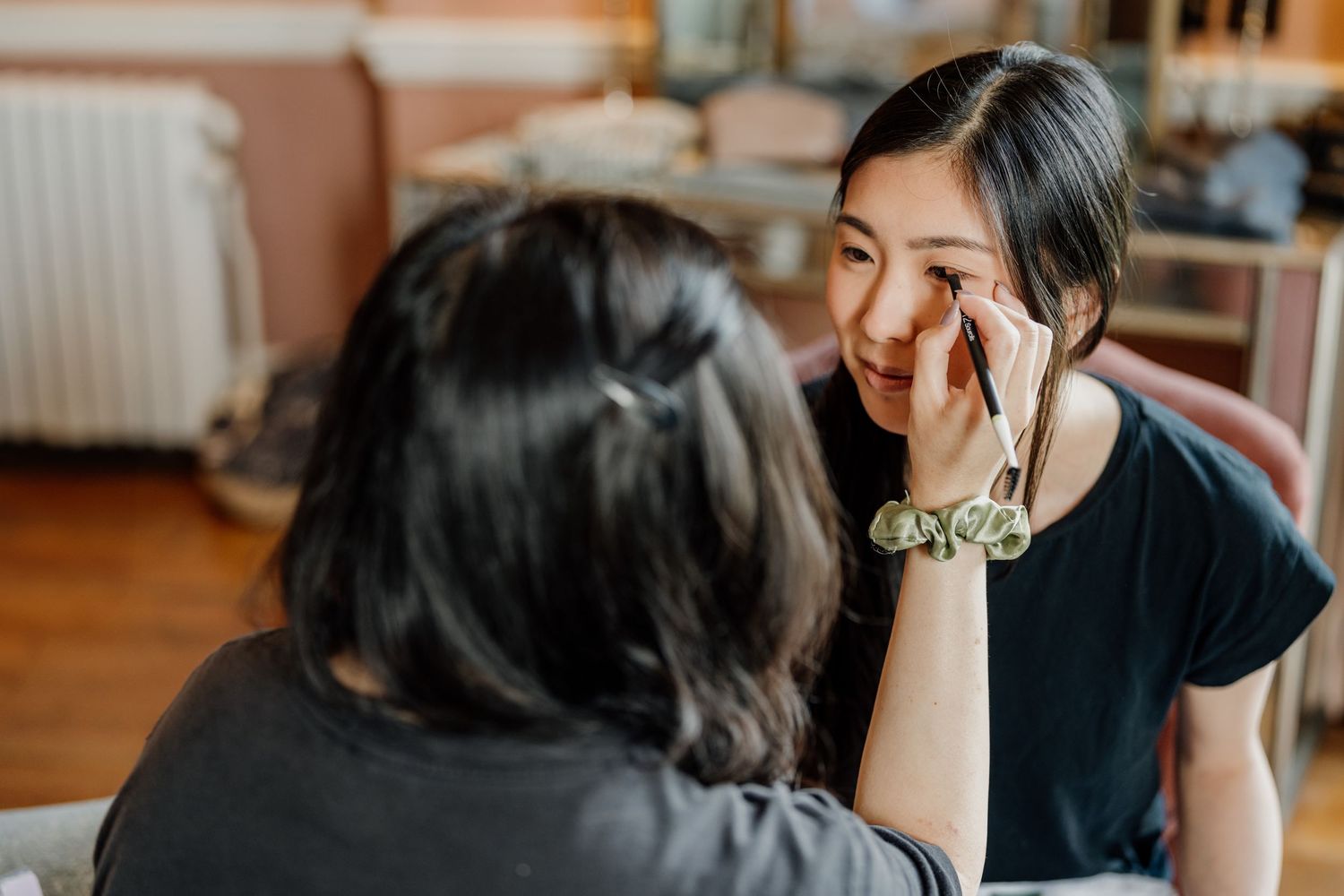 Person getting professional makeup applied with brushes during wedding preparation.