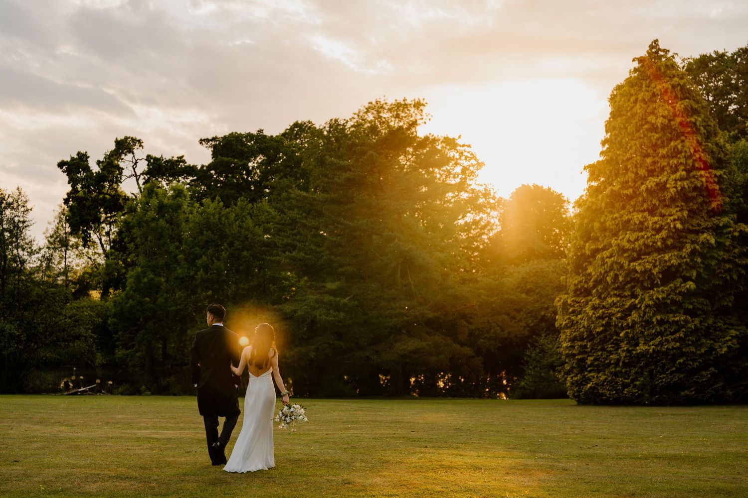 Golden sunset illuminates a scenic wedding venue with rolling hills and trees in the background.